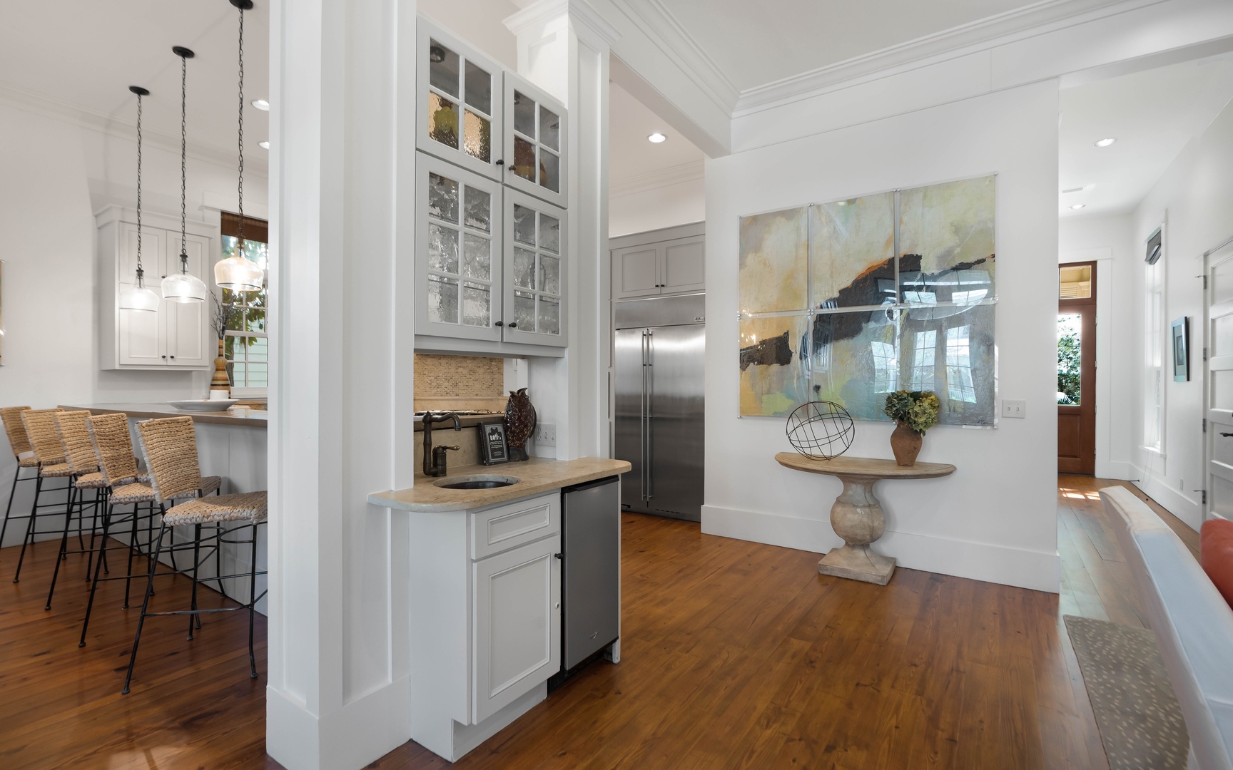 You'll love this bright, open kitchen with gleaming white cabinets, hardwood floors, and a charming breakfast bar perfect for morning coffee.