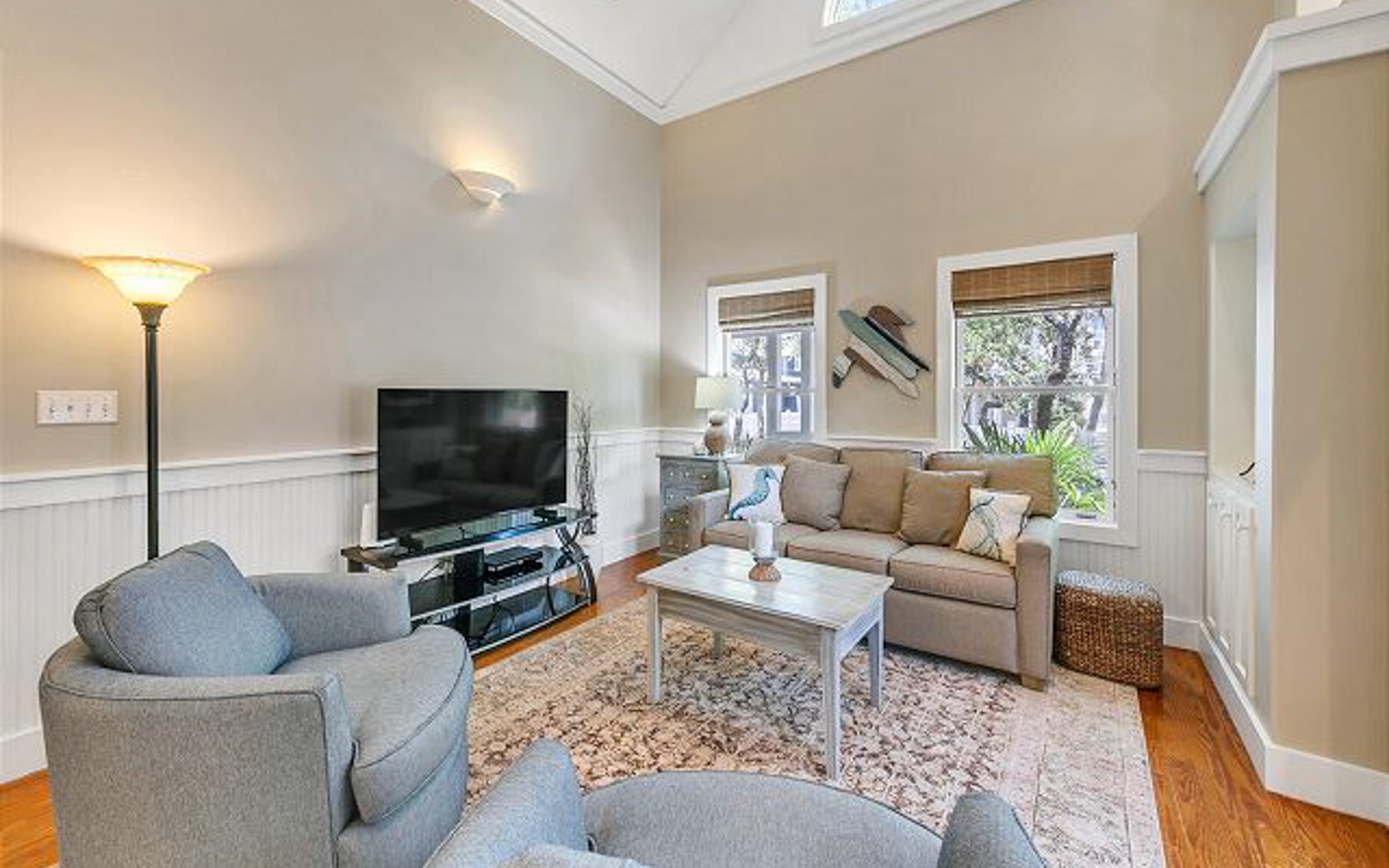 Relax in your bright living space with plush seating, natural light streaming through bamboo blinds, and entertainment ready for cozy evenings together.