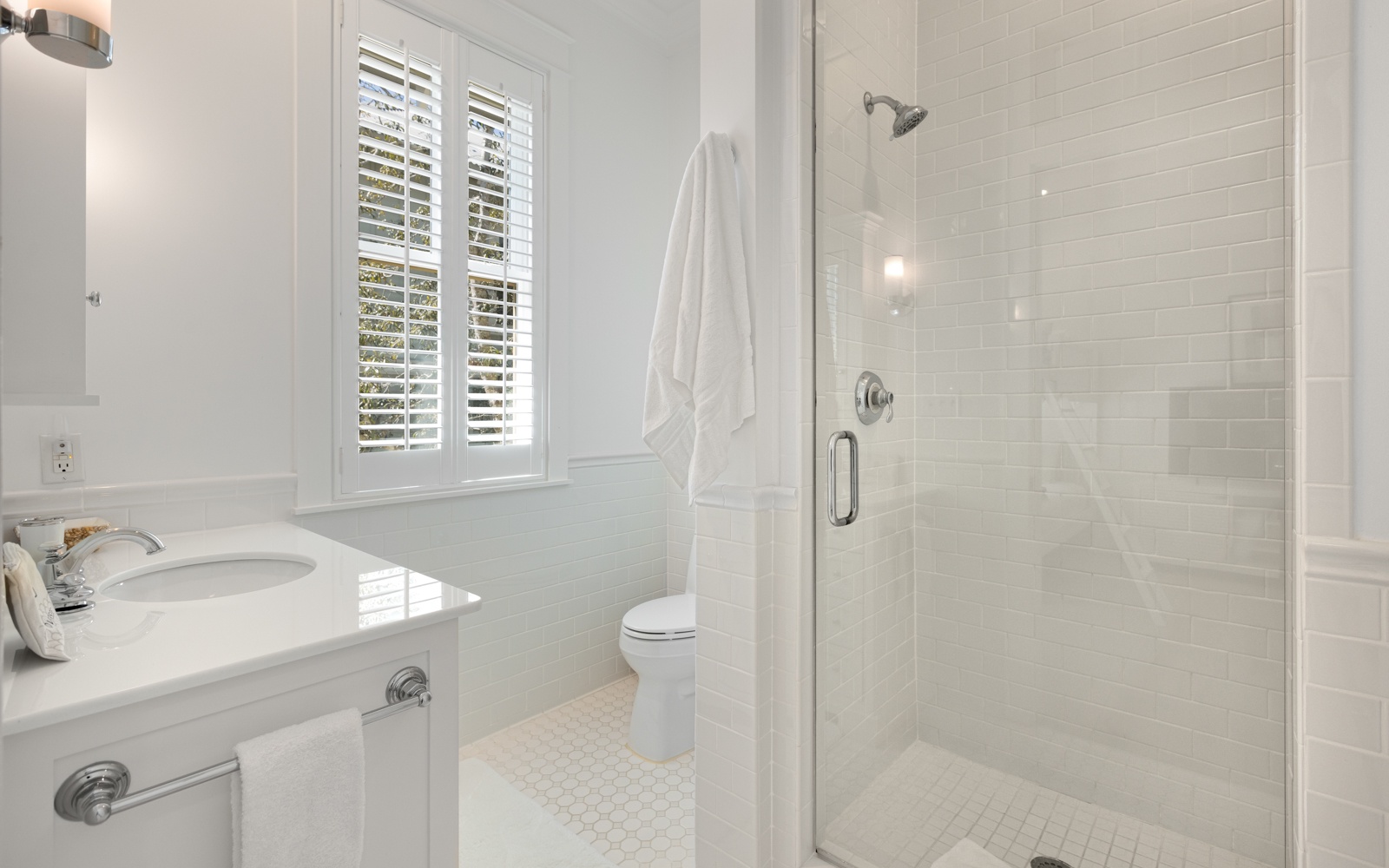 Step into your pristine bathroom featuring a spacious glass shower, crisp white finishes, and fresh towels waiting for your arrival.