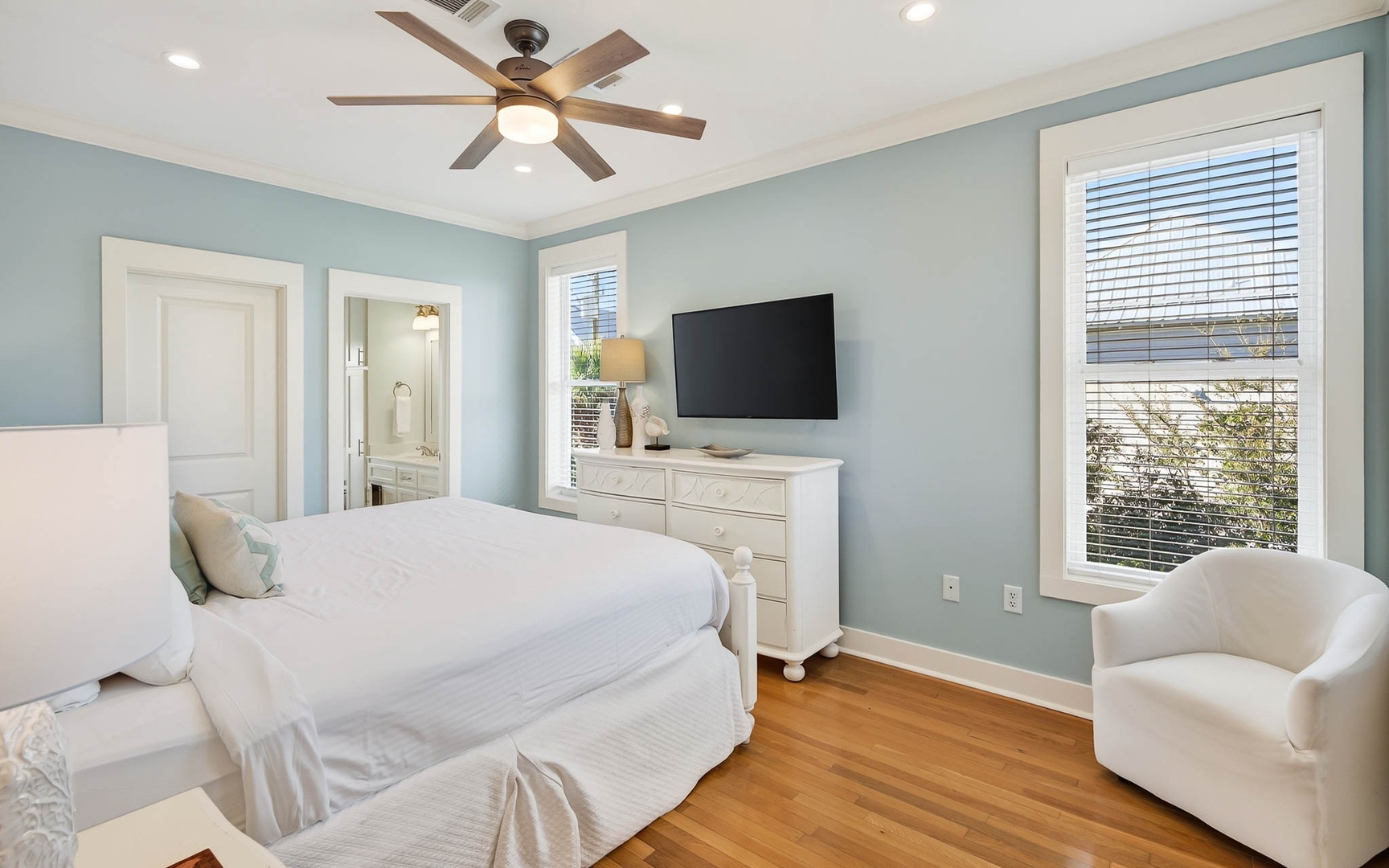 Unwind in your serene bedroom featuring soothing blue walls, crisp white linens, and modern amenities for restful nights.