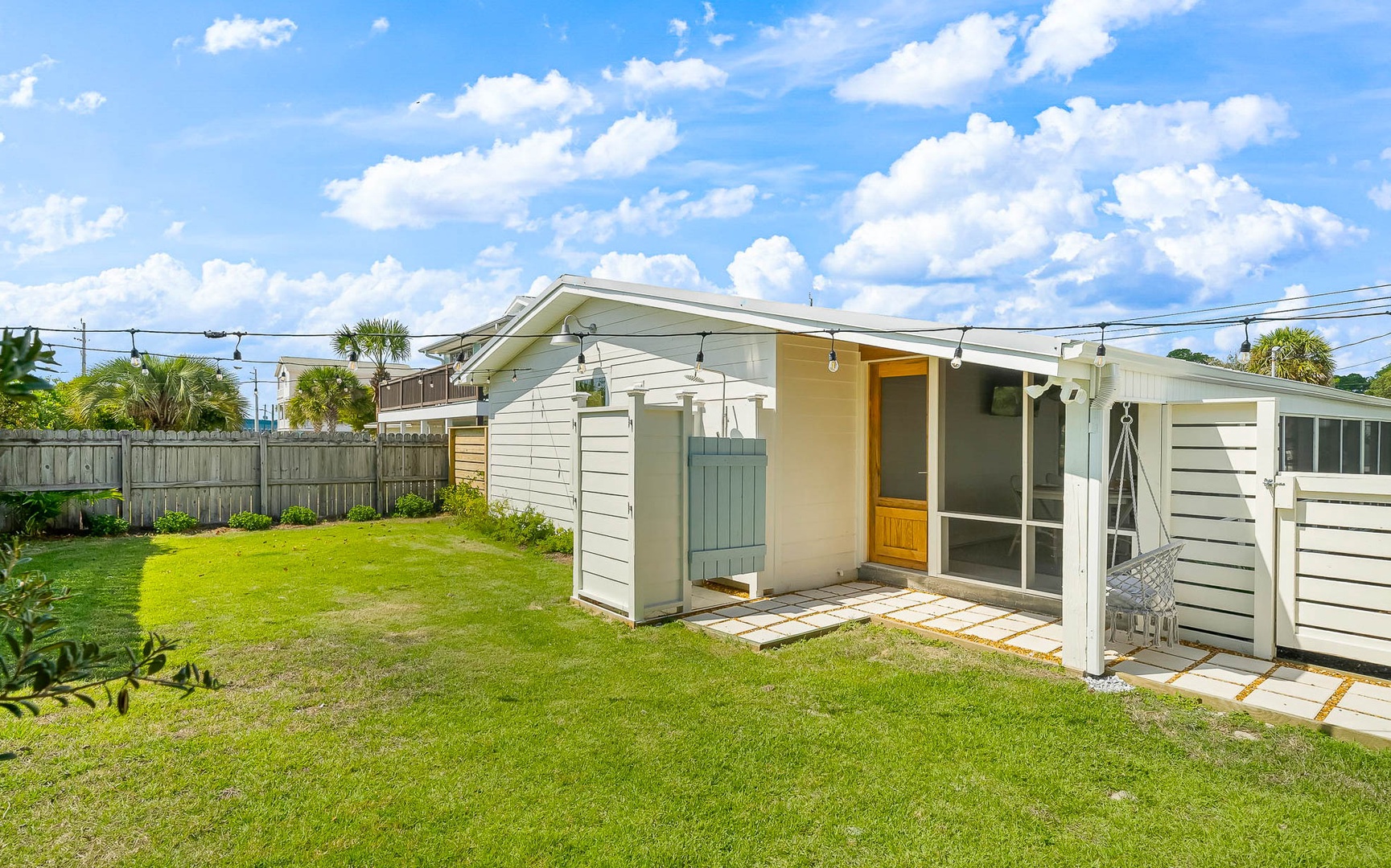 Enjoy your own private backyard oasis with lush green lawn and charming outdoor shower space under sunny Florida skies.