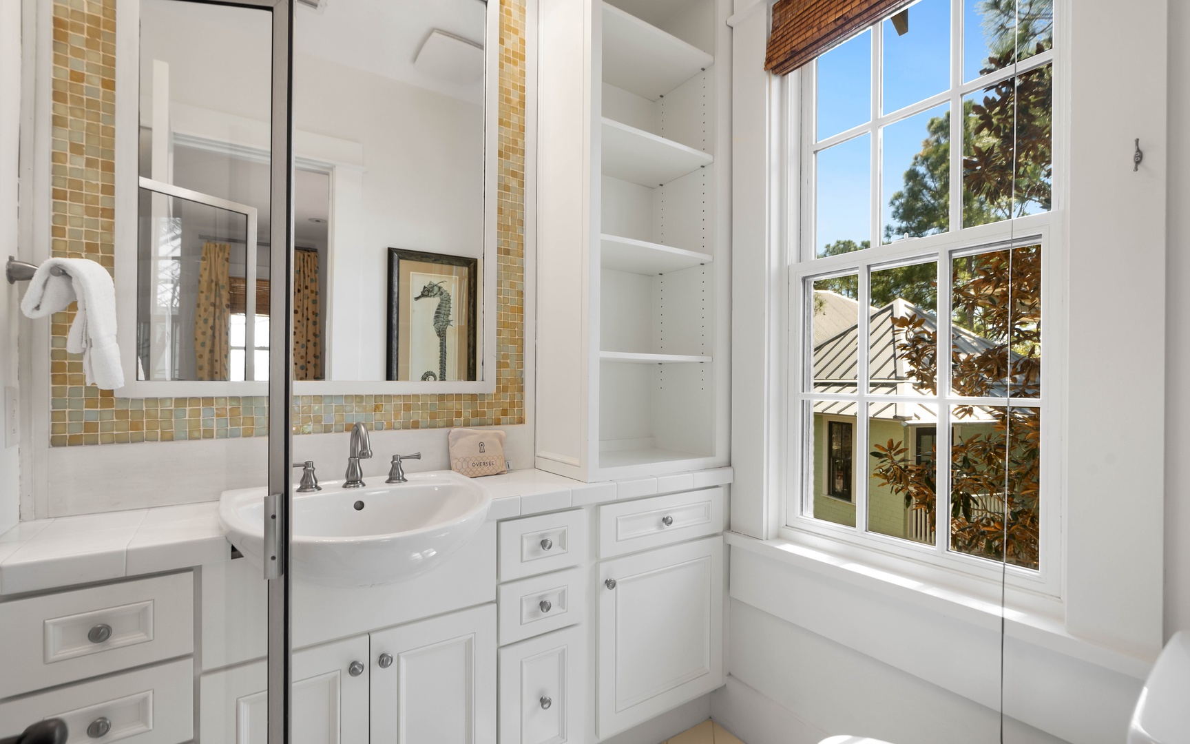 Refresh in your bright, beautifully appointed bathroom featuring elegant tile work, ample storage, and natural light streaming through charming windows.