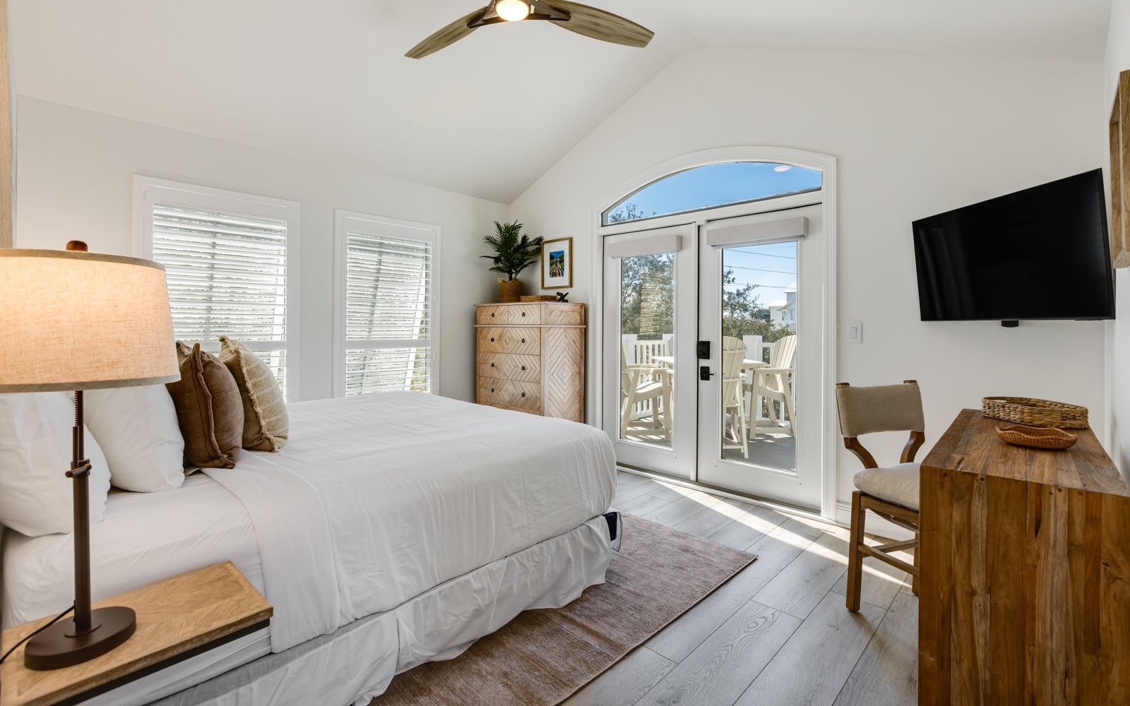 Your peaceful bedroom retreat features crisp white linens, warm wood accents, and French doors opening to your private balcony.