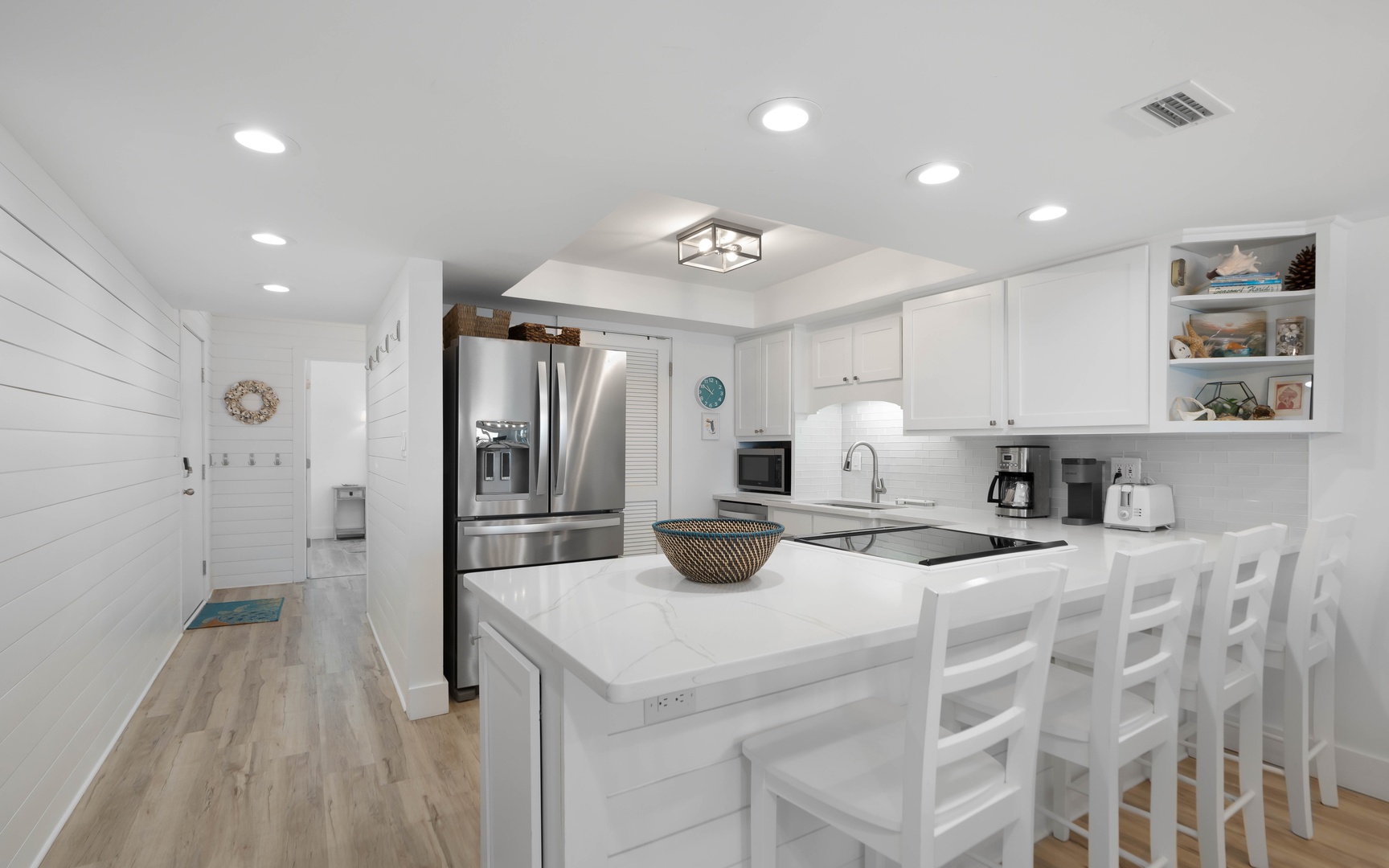 Your bright, modern kitchen awaits with sleek white cabinetry, stainless steel appliances, and a spacious island perfect for morning coffee or evening meals.