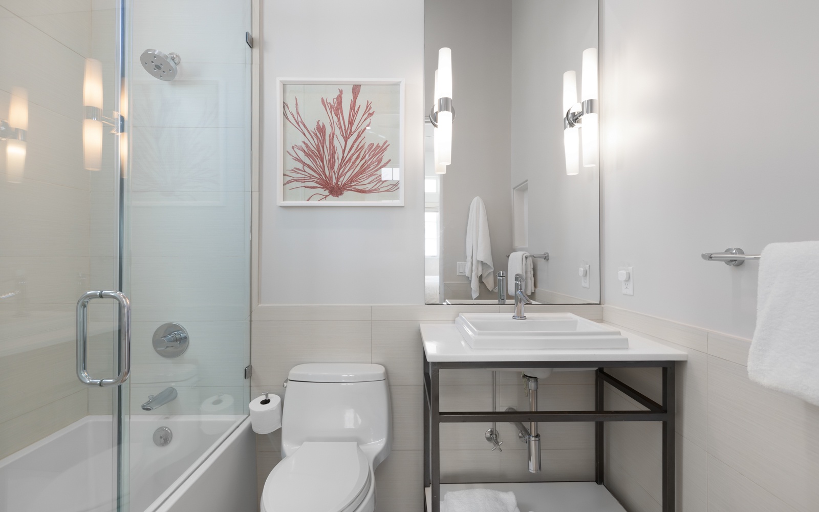 Your modern bathroom features a sleek glass shower, stylish vanity, and coastal artwork creating a spa-like retreat.