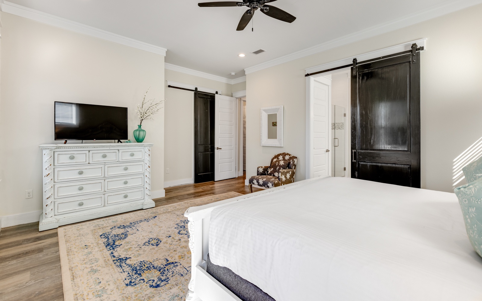 Unwind in your spacious bedroom with charming barn doors, cozy seating, and modern amenities for the perfect retreat.