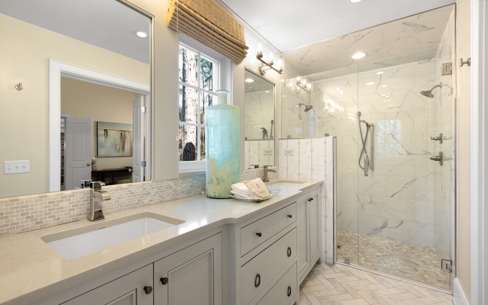 Indulge in luxury with this spa-like bathroom featuring dual vanities, elegant marble shower, and soothing coastal touches.