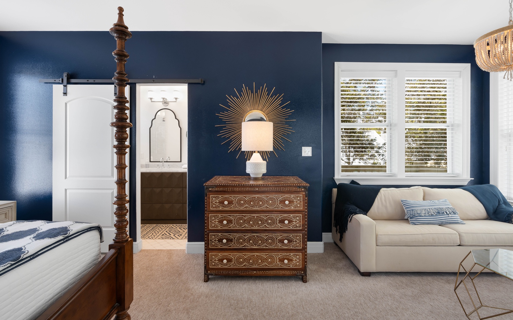 Unwind in your elegant bedroom featuring rich navy walls, a four-poster bed, and cozy seating area perfect for morning coffee.