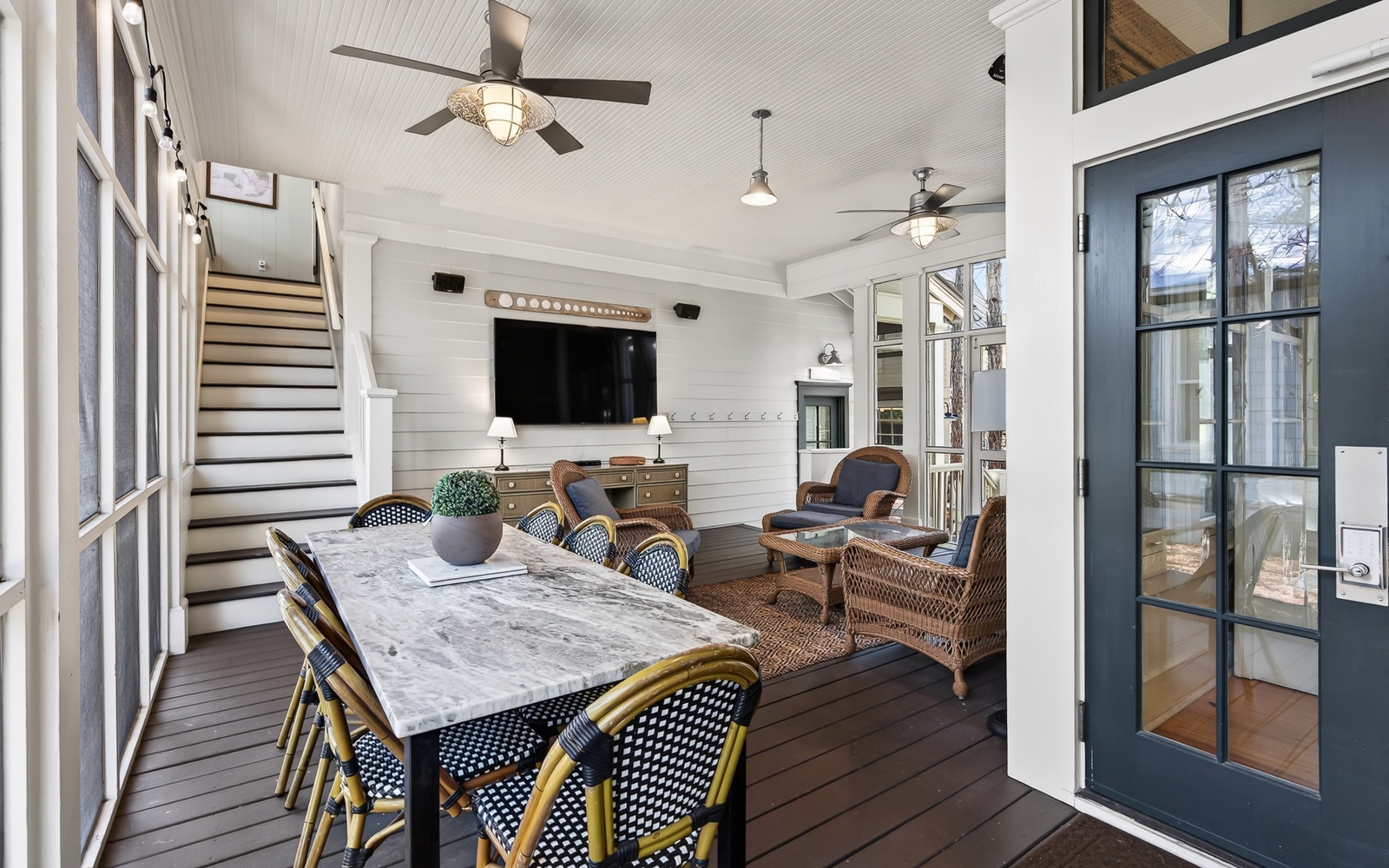 Your elegant screened porch offers the perfect blend of comfort and coastal charm with ceiling fans, dining space, and cozy seating.