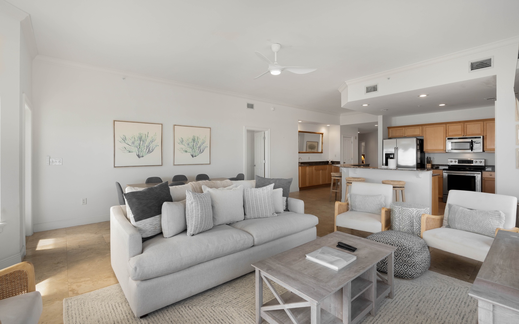 Relax in your stylish open-plan living space with coastal artwork, plush seating, and a modern kitchen perfect for preparing meals together.