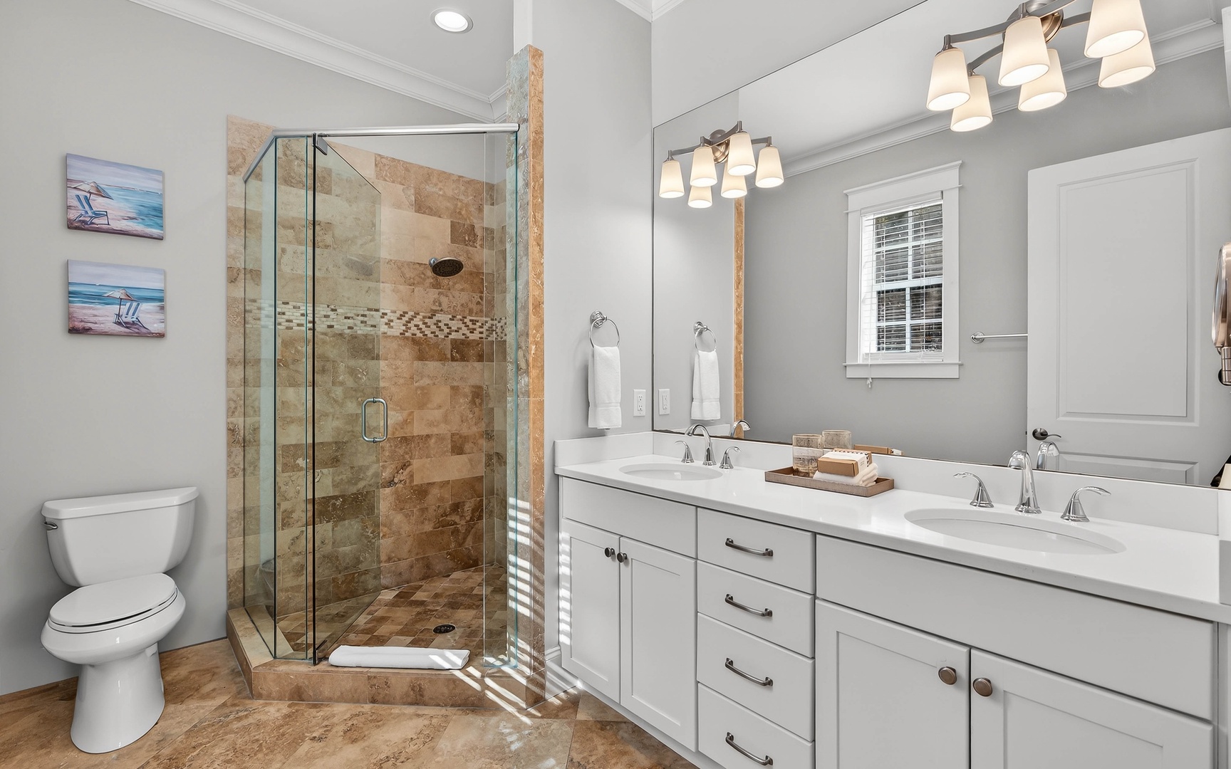 Your spacious bathroom features dual vanities, a luxurious glass-enclosed shower with mosaic accents, and elegant fixtures for your comfort.