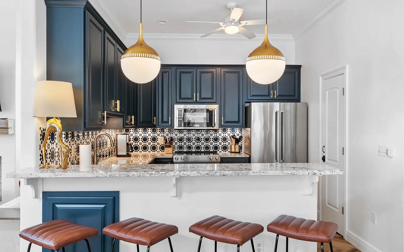 Your gourmet kitchen features navy cabinets, marble counters, and gold pendant lights—perfect for preparing memorable meals during your stay.