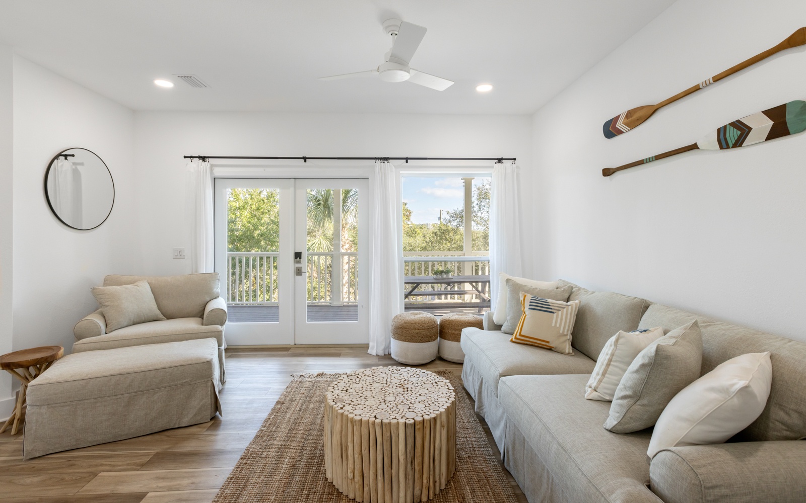 Sink into plush sofas and enjoy natural light streaming through French doors to your private balcony in this serene coastal-inspired living space.