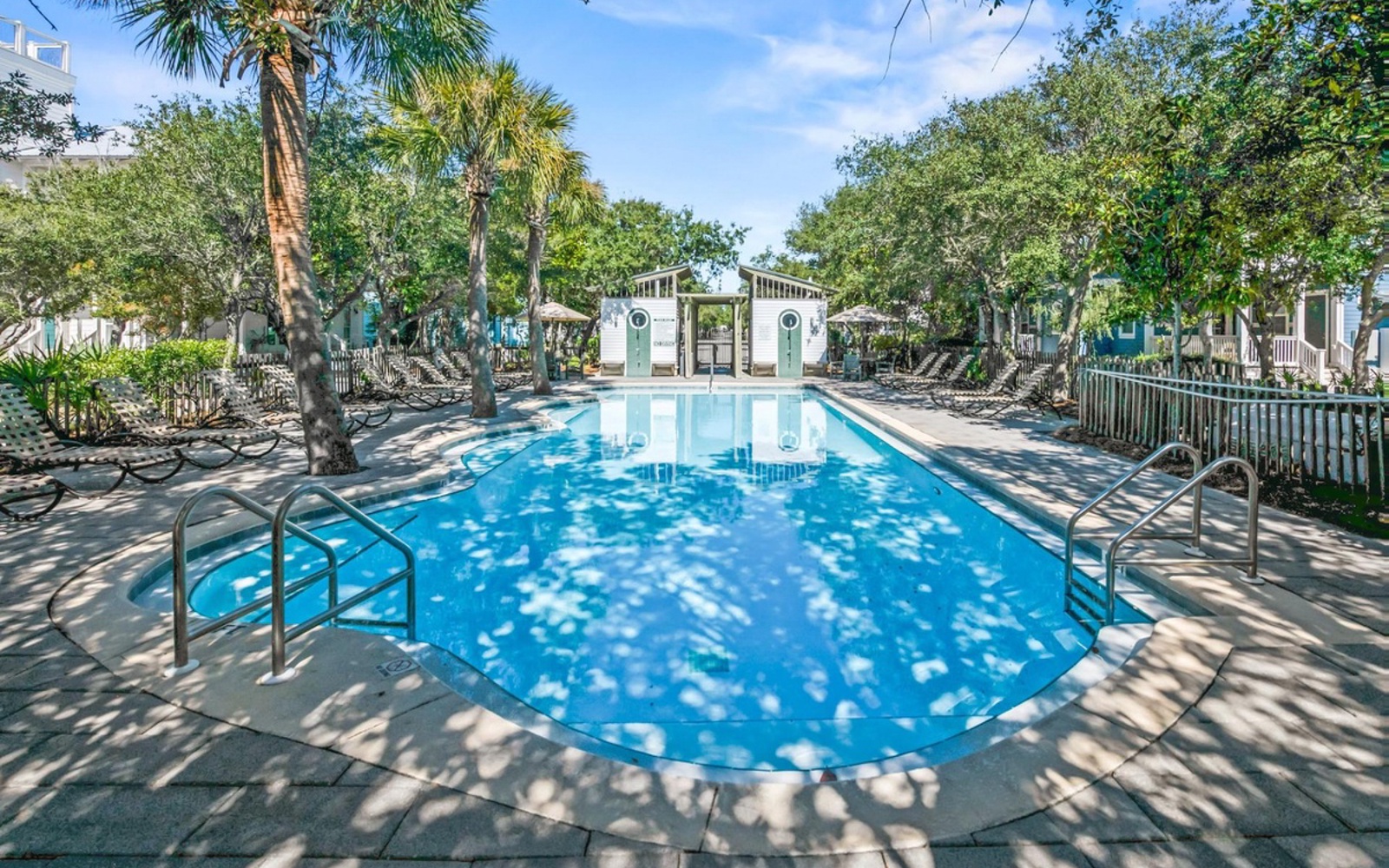 A sparkling communal pool surrounded by tropical palms and lounge chairs, creating the perfect retreat for relaxation.