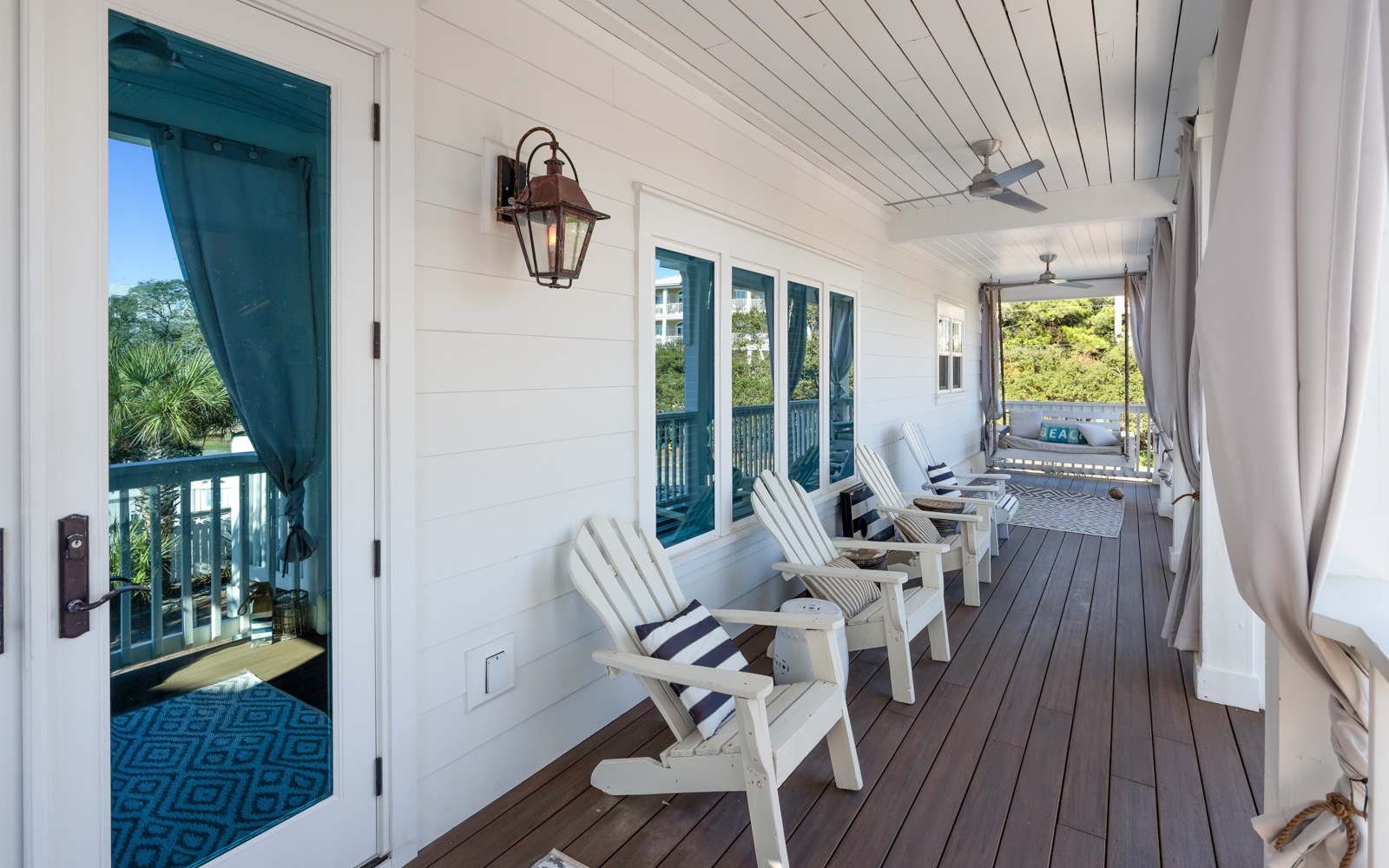 Relax on your private covered porch with white Adirondack chairs and coastal breezes, overlooking lush tropical greenery.