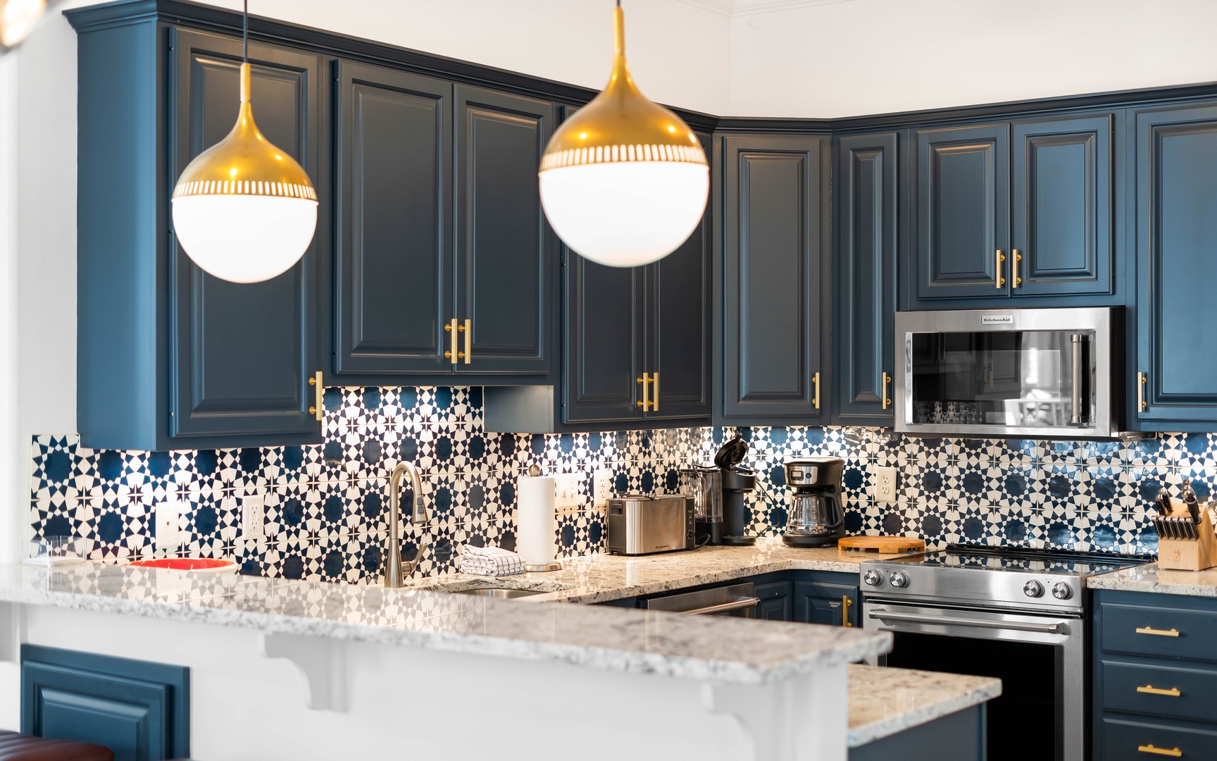 Your stylish kitchen features bold blue cabinetry, stunning patterned backsplash, and gleaming marble counters perfect for cooking memorable meals.