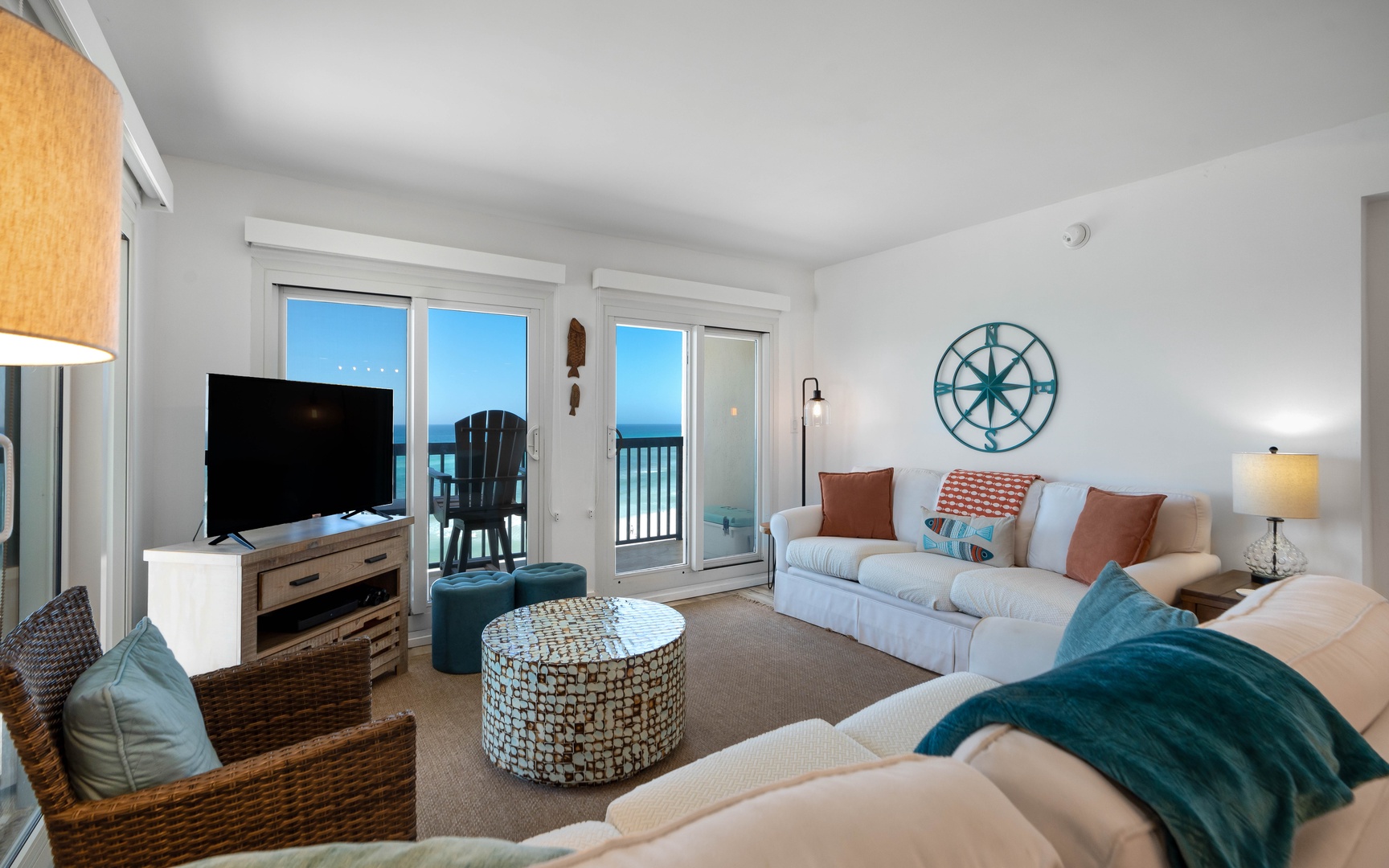 Sink into coastal comfort in your beautifully appointed living room, where ocean breezes flow through sliding doors and nautical touches create the perfect seaside retreat.
