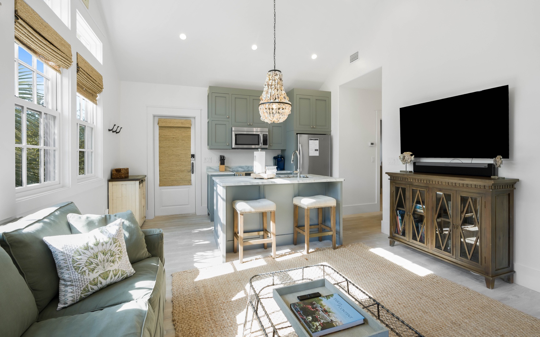 Your elegant open-plan living space features soft green hues, natural light, and a crystal chandelier creating the perfect retreat.