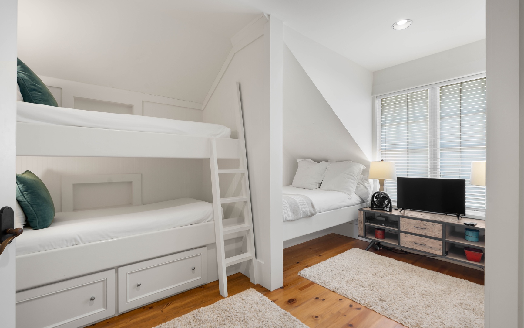 Your cozy bunk room features built-in beds with storage drawers, soft rugs on hardwood floors, and entertainment center for relaxing evenings.
