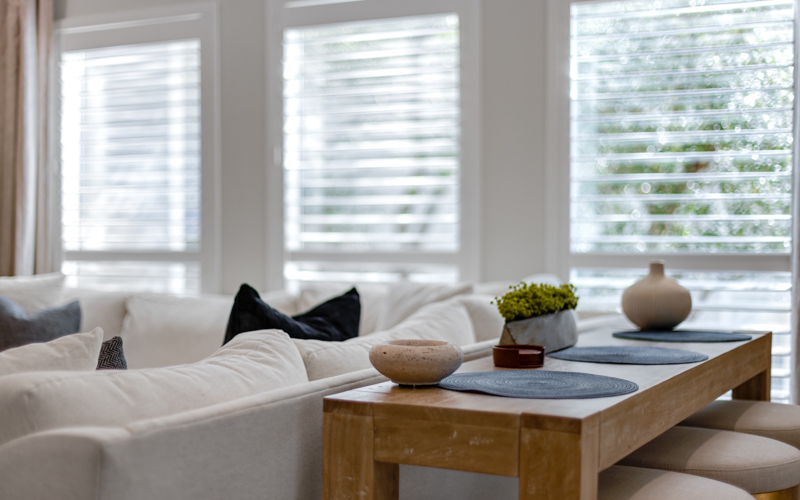 Sink into plush white sofas and unwind in your bright, airy living space with natural light filtering through elegant shutters.