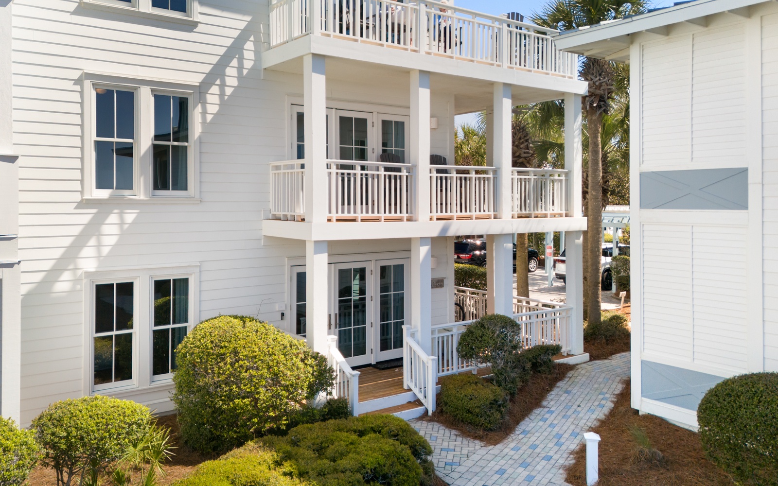 White coastal architecture with private balconies overlooks lush tropical landscaping and perfectly manicured gardens.