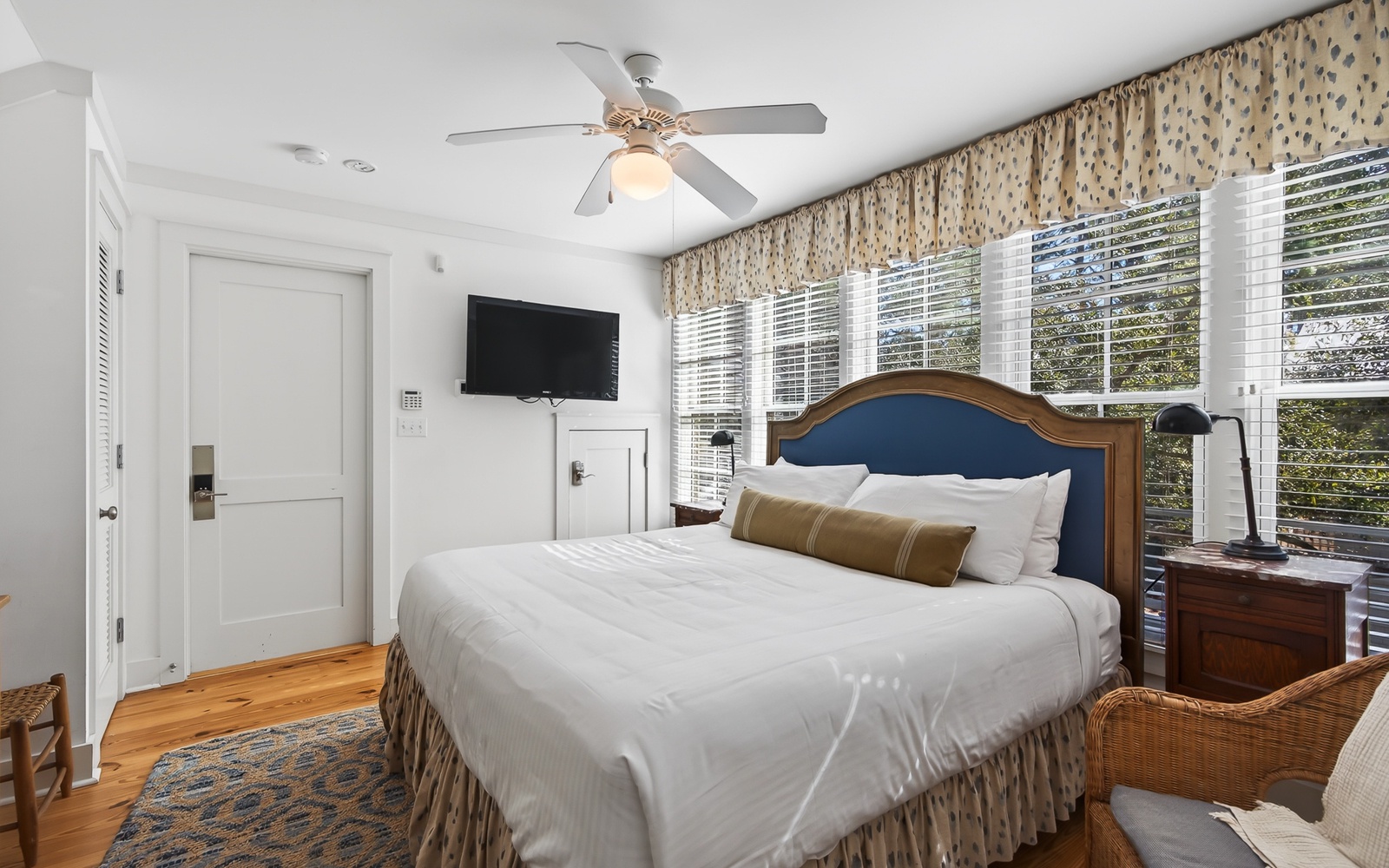 Unwind in your bright bedroom with crisp linens, charming decor, and peaceful garden views through plantation shutters.