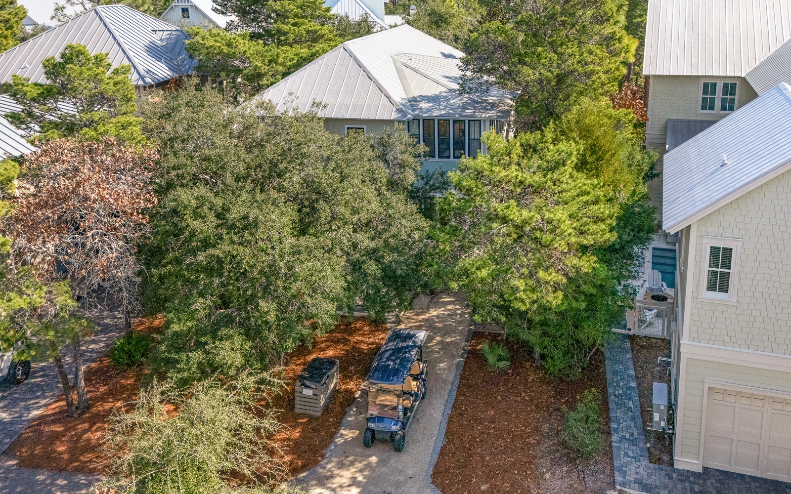 Charming coastal community with mature trees creating a peaceful neighborhood setting among well-maintained homes with metal roofing.