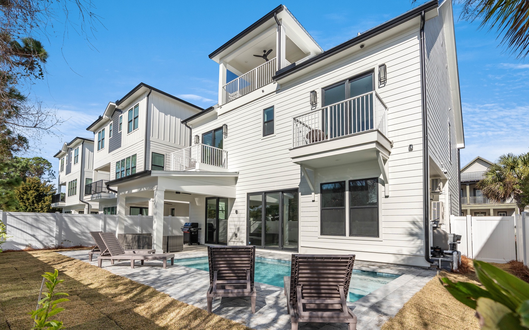 Modern multi-story vacation home with private pool, outdoor lounging area, and tropical landscaping in a peaceful neighborhood setting.