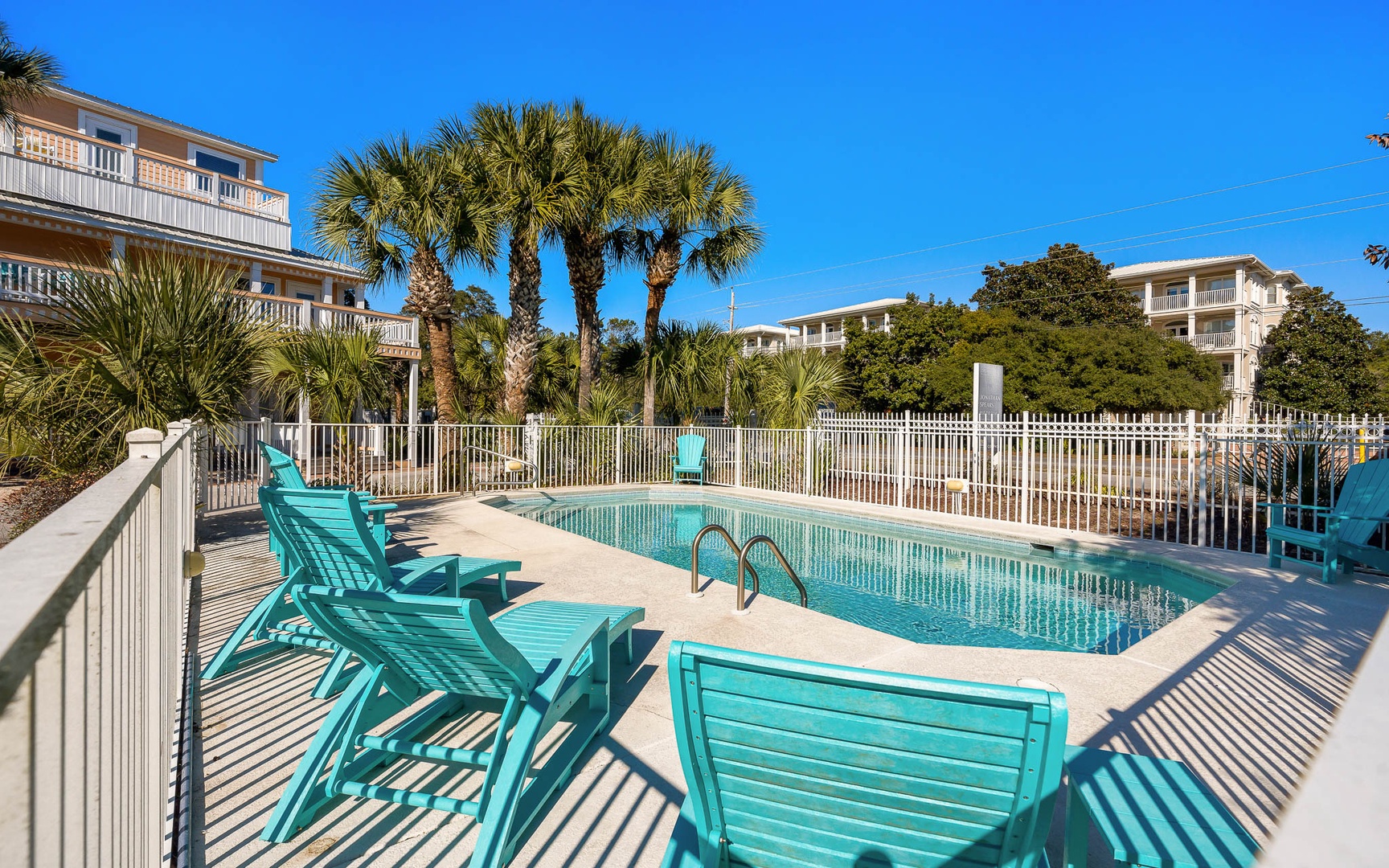 Sparkling pool surrounded by turquoise loungers and swaying palms creates your perfect tropical retreat under endless blue skies.