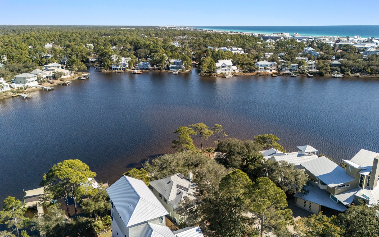 Stunning aerial view of waterfront vacation homes nestled among lush trees along pristine lake waters, just minutes from the beach.
