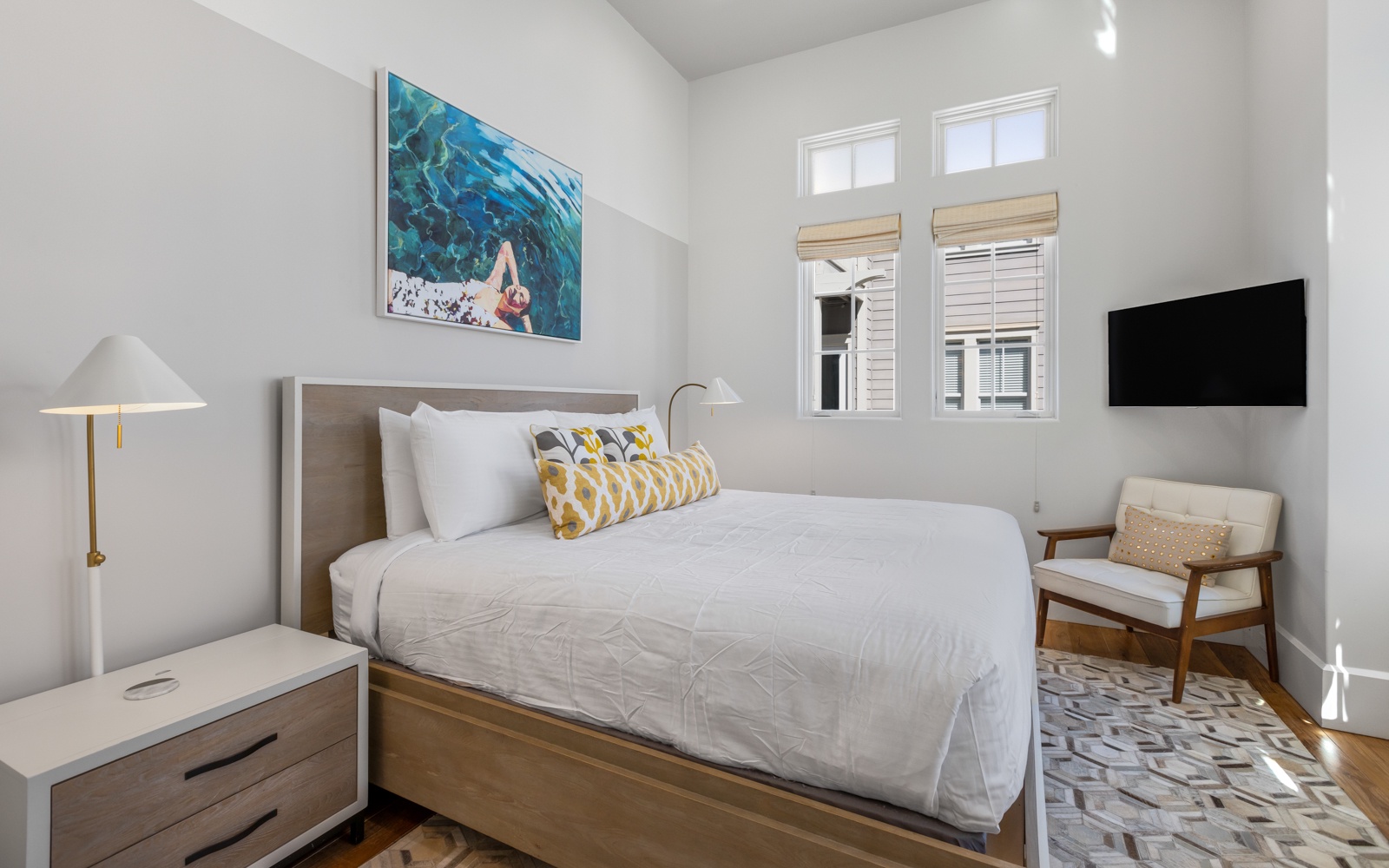 Sink into crisp linens and enjoy peaceful mornings in your bright bedroom, complete with modern amenities and stylish coastal artwork.