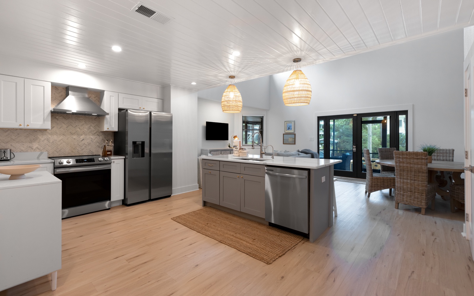 Gather with loved ones in this stunning open-concept kitchen featuring warm wood floors, pendant lighting, and stainless steel appliances.