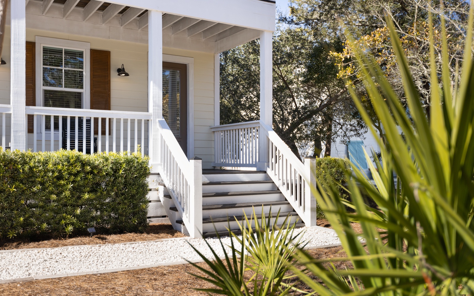 Charming front porch with white railings and lush landscaping creates a welcoming entrance to your peaceful retreat.