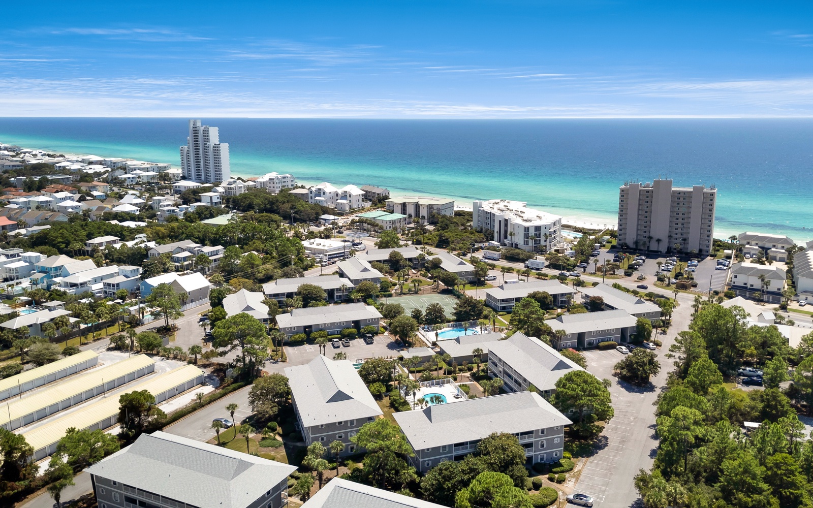 Coastal community with pristine beaches and turquoise waters, featuring residential buildings and high-rise accommodations near the shoreline.