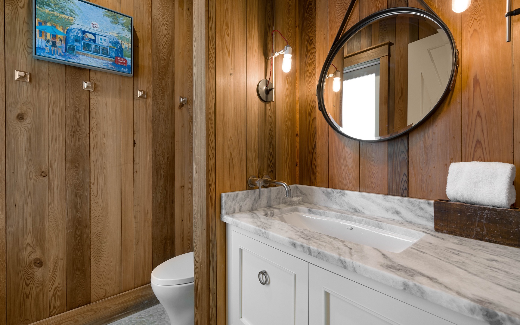 Unwind in your elegant bathroom featuring warm wood walls, marble countertops, and modern fixtures for your comfort.