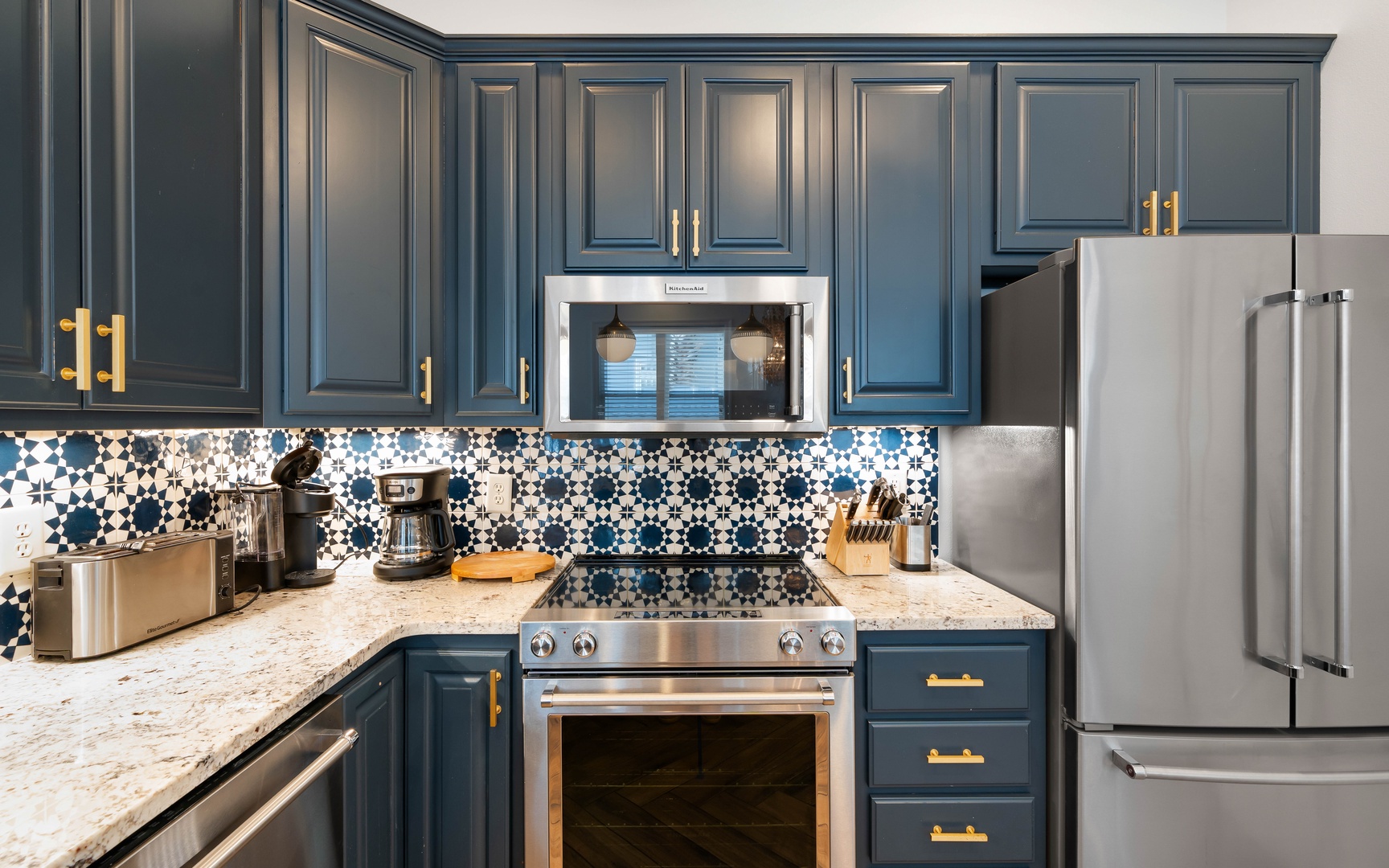 Your stunning kitchen features rich navy cabinets with gold accents and beautiful patterned tile backsplash, perfect for creating memorable meals.