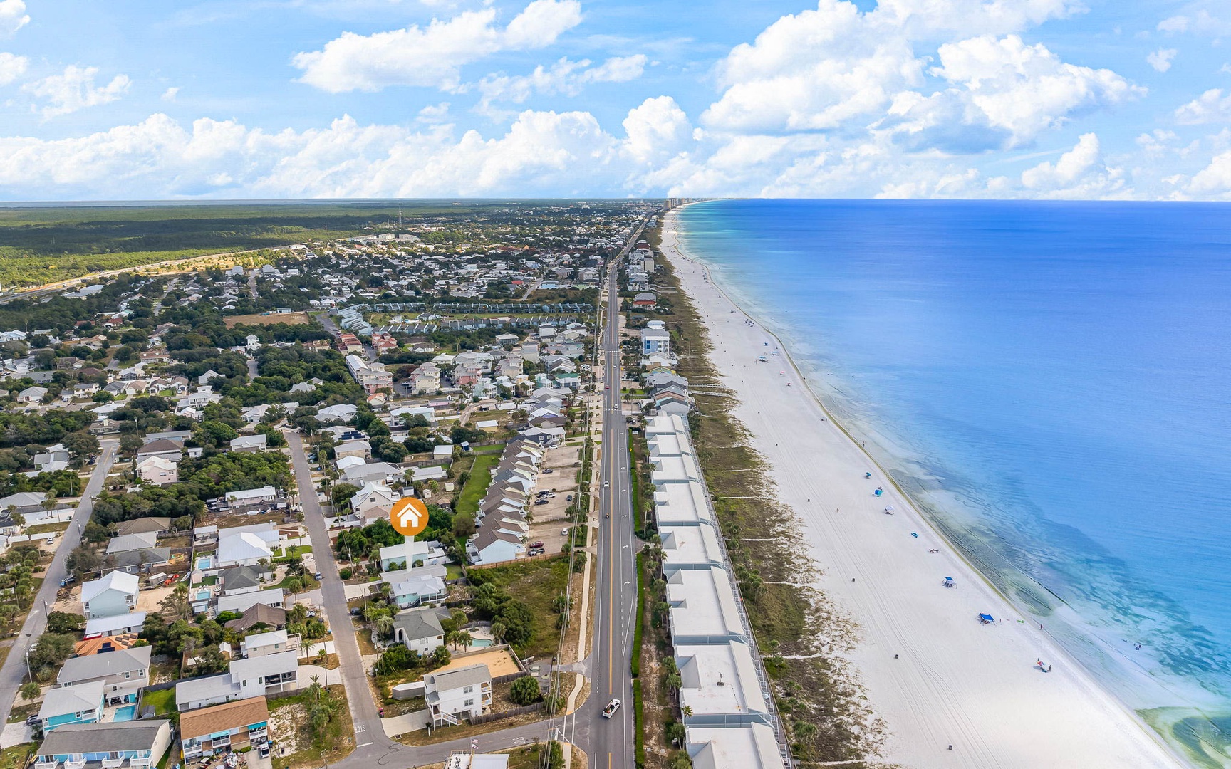 Aerial view of coastal community with pristine beaches stretching along turquoise waters, surrounded by residential neighborhoods and natural landscapes.
