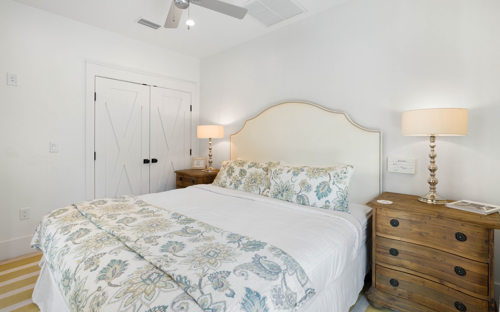 Sink into crisp white linens adorned with soft botanical prints in your serene bedroom retreat, complete with warm wood furnishings and gentle lighting.