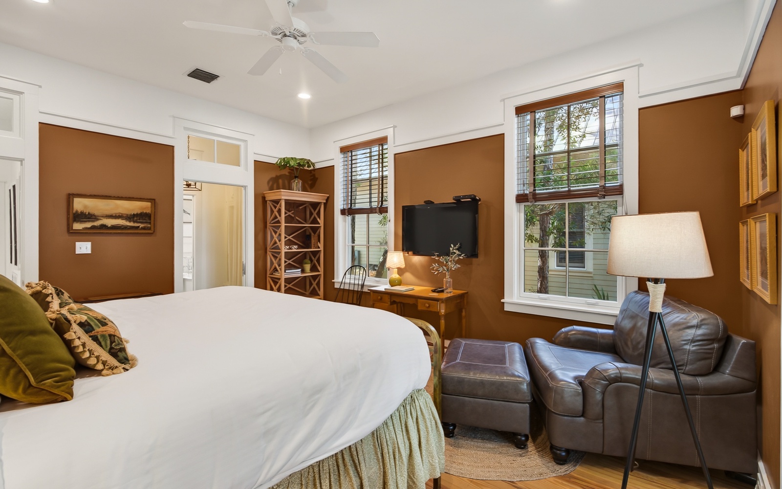 Unwind in your cozy bedroom with warm earth tones, leather seating, and natural light streaming through lovely windows.