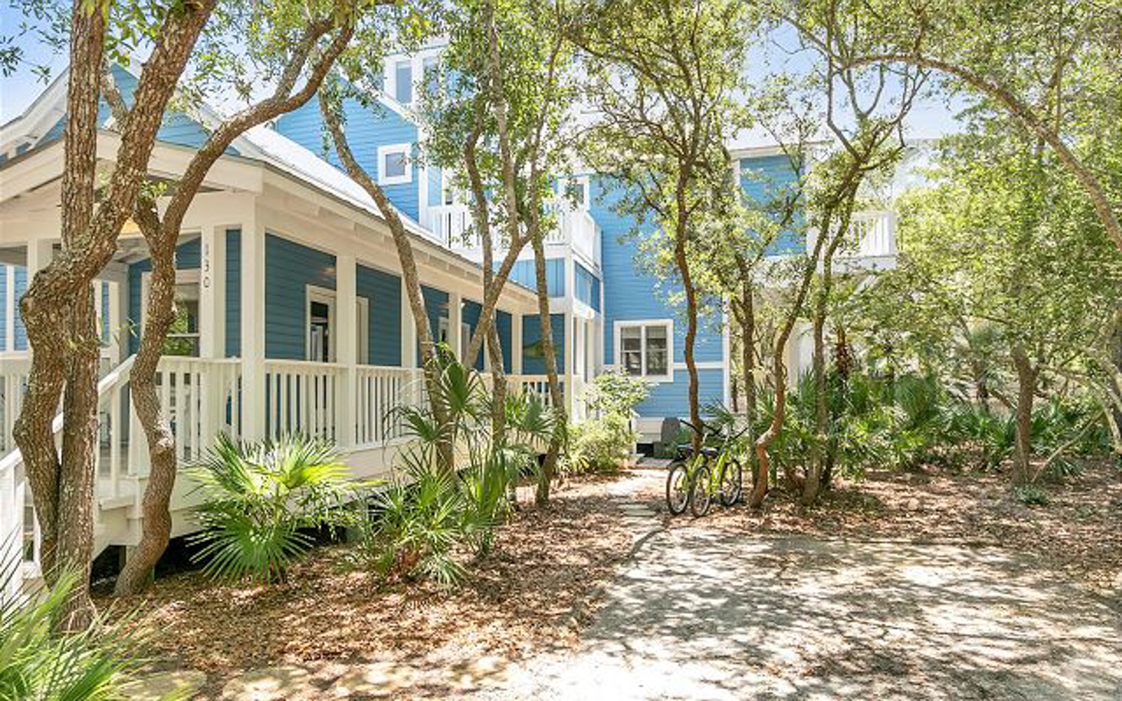 Charming coastal cottages nestled among mature trees and tropical landscaping create a peaceful neighborhood setting.