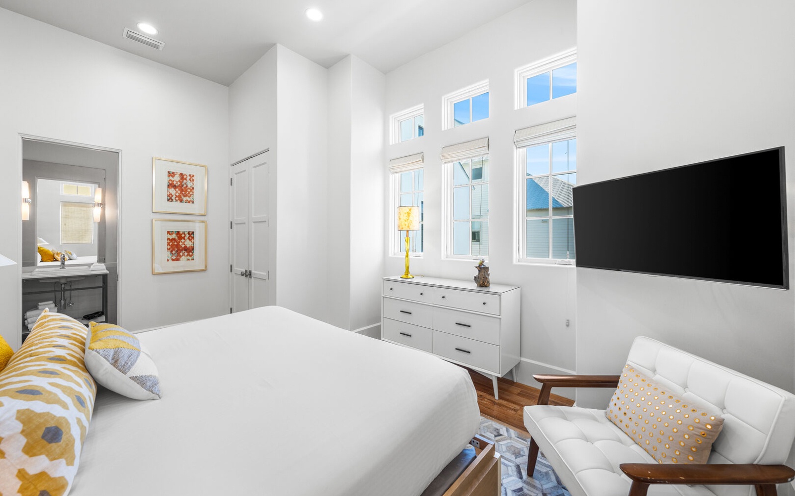 Rest peacefully in your bright, airy bedroom featuring crisp white linens and cheerful yellow accents.