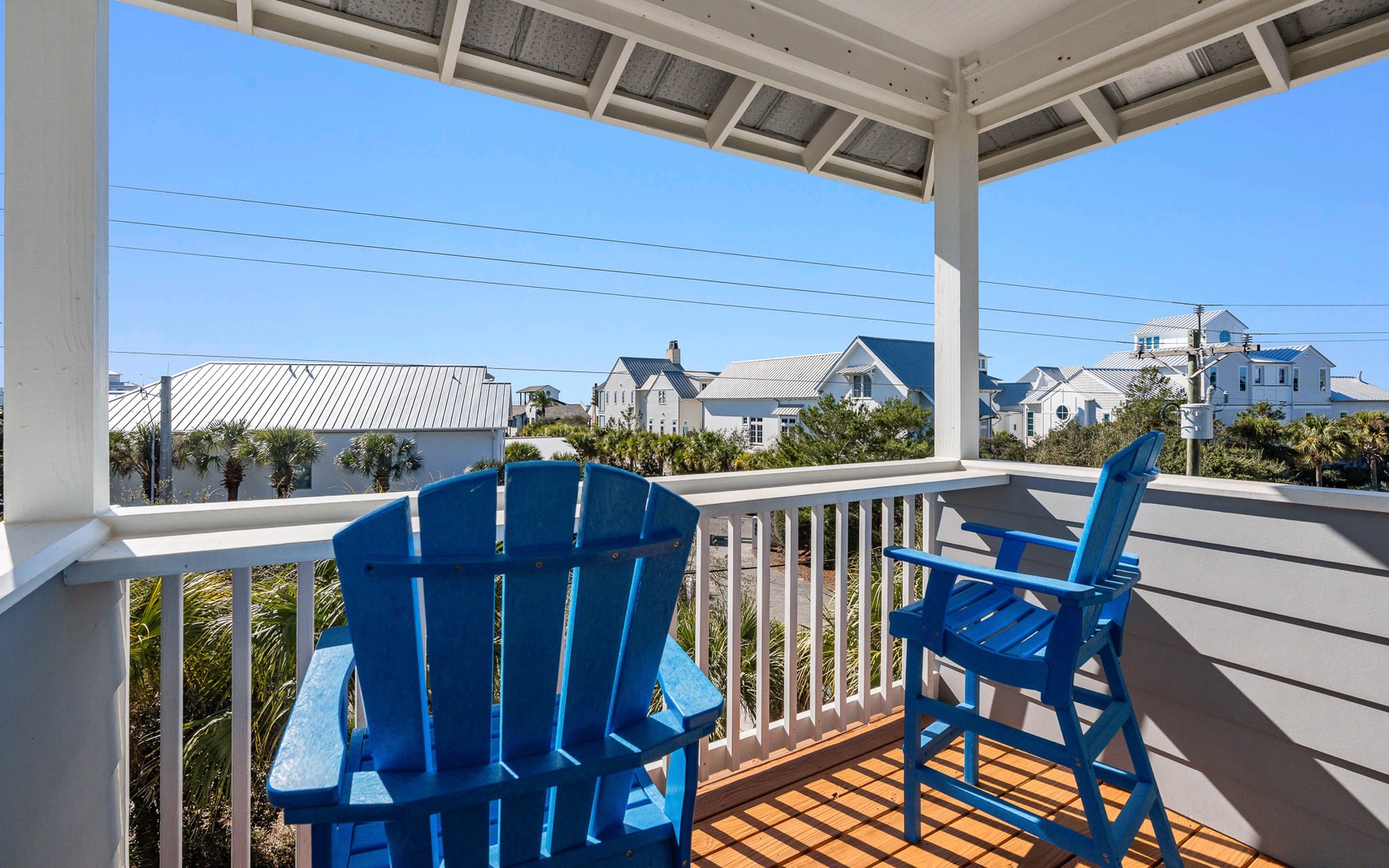 Sip your morning coffee in these cheerful blue Adirondack chairs while soaking up coastal charm and neighborhood views.