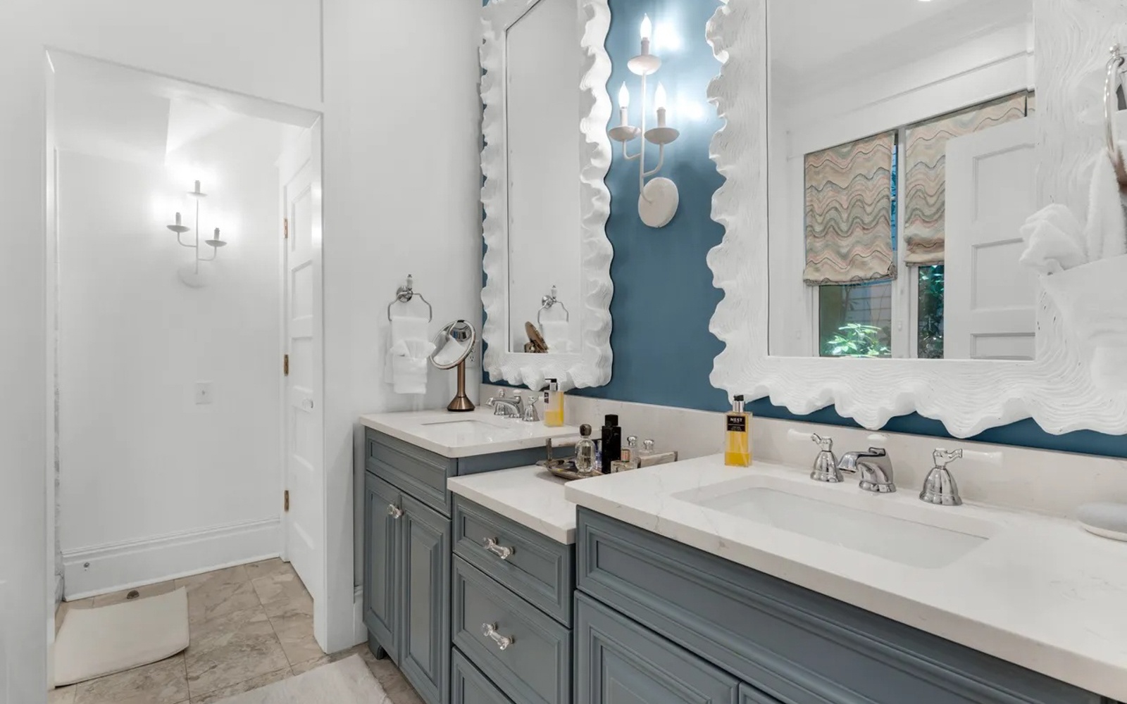 Freshen up in your elegant bathroom featuring dual vanities, stylish scalloped mirrors, and soothing coastal-inspired colors.