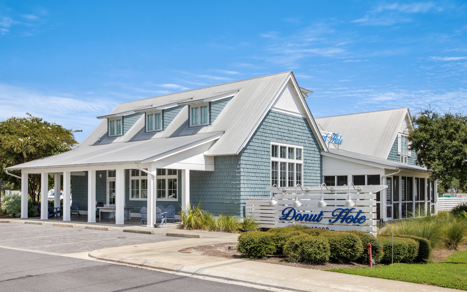 Charming coastal property featuring traditional shingle siding and welcoming covered porches surrounded by manicured landscaping.