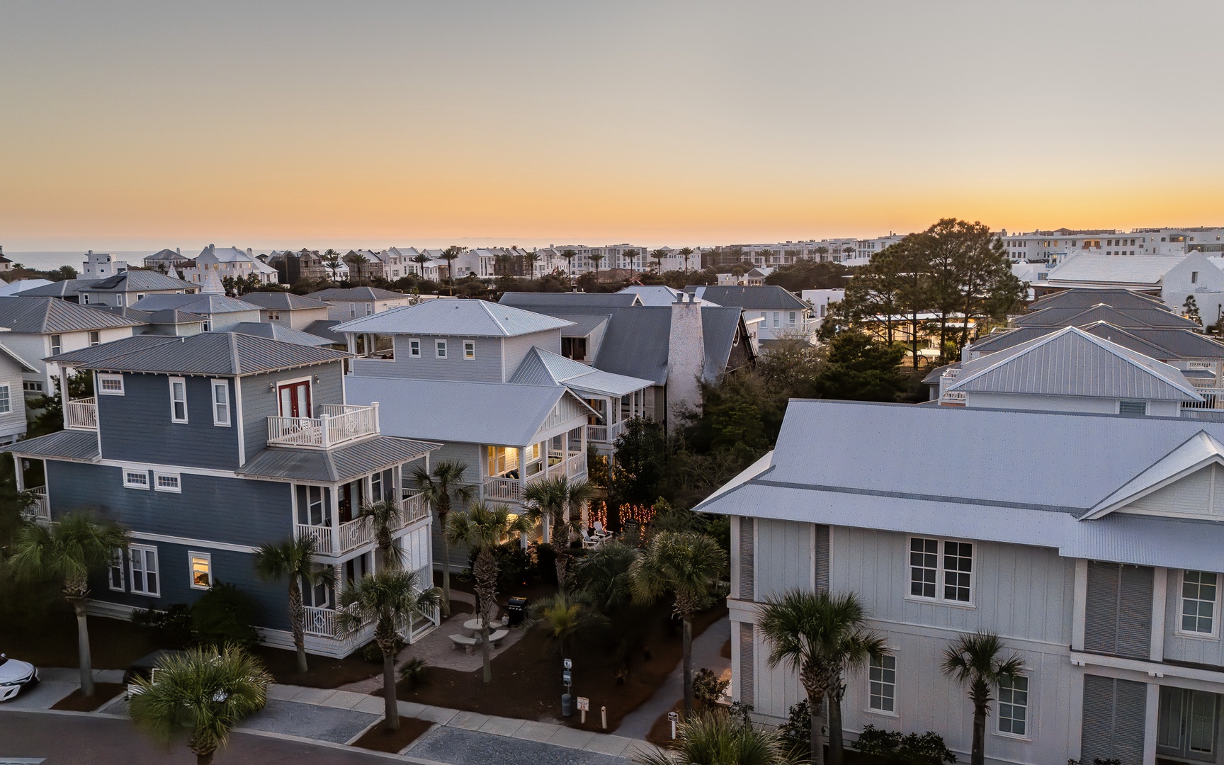 Aerial view of coastal residential neighborhood with palm trees and houses at sunset.