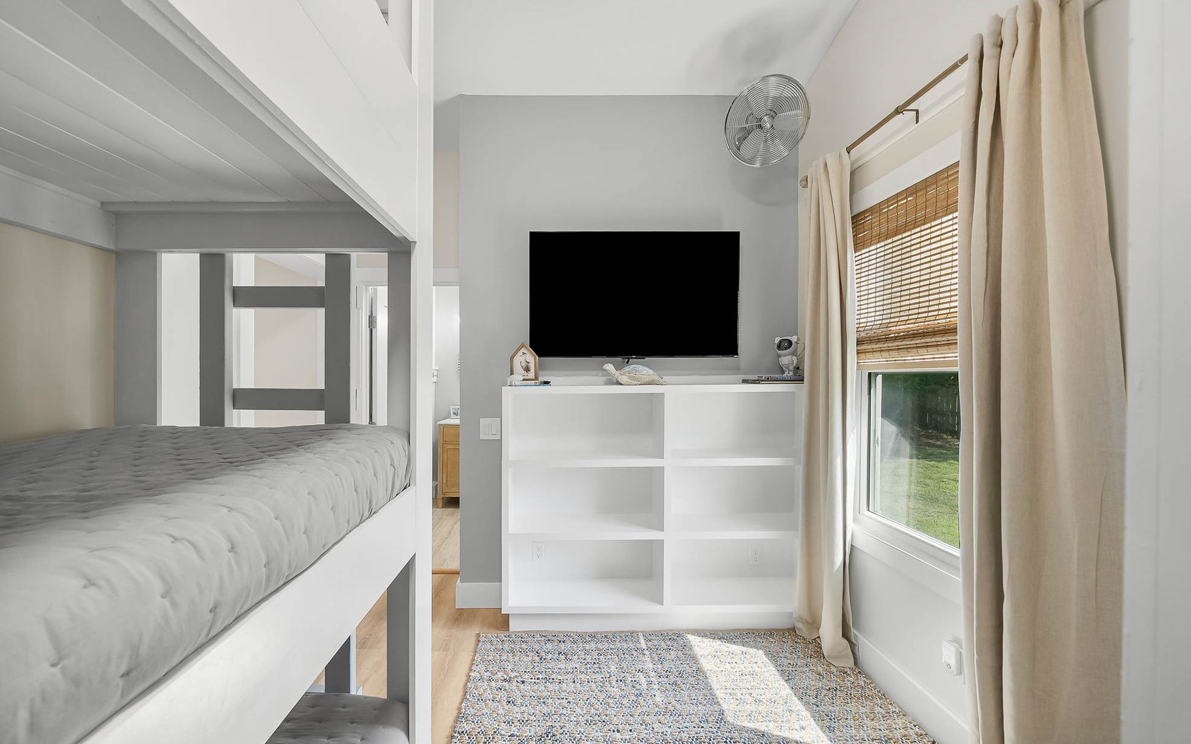 Unwind in your cozy room featuring a convenient bunk bed, entertainment center, and peaceful garden views through bamboo blinds.