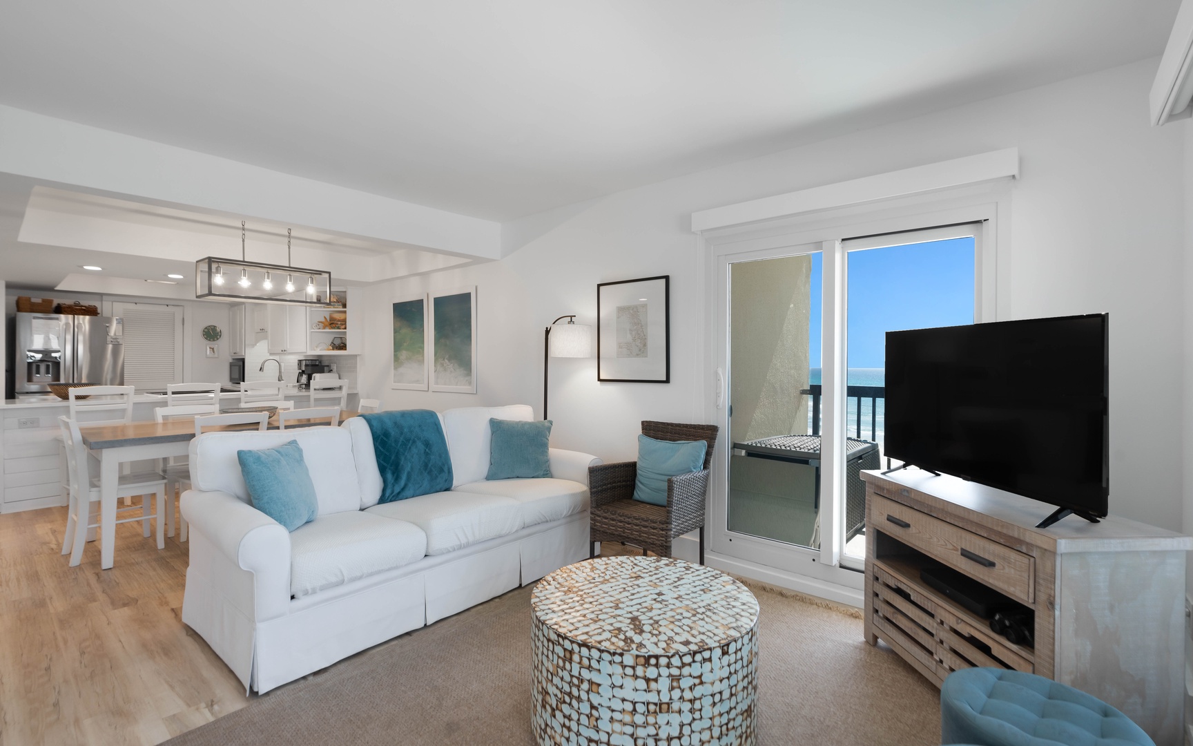 Sink into plush seating while ocean breezes flow through your private balcony doors in this bright, coastal-inspired living space.