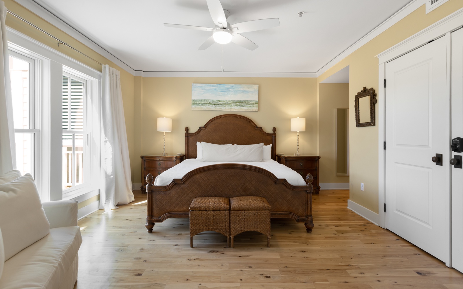 Sink into luxurious comfort in your elegant bedroom, where natural light flows through crisp white curtains and warm wood floors create a peaceful retreat.