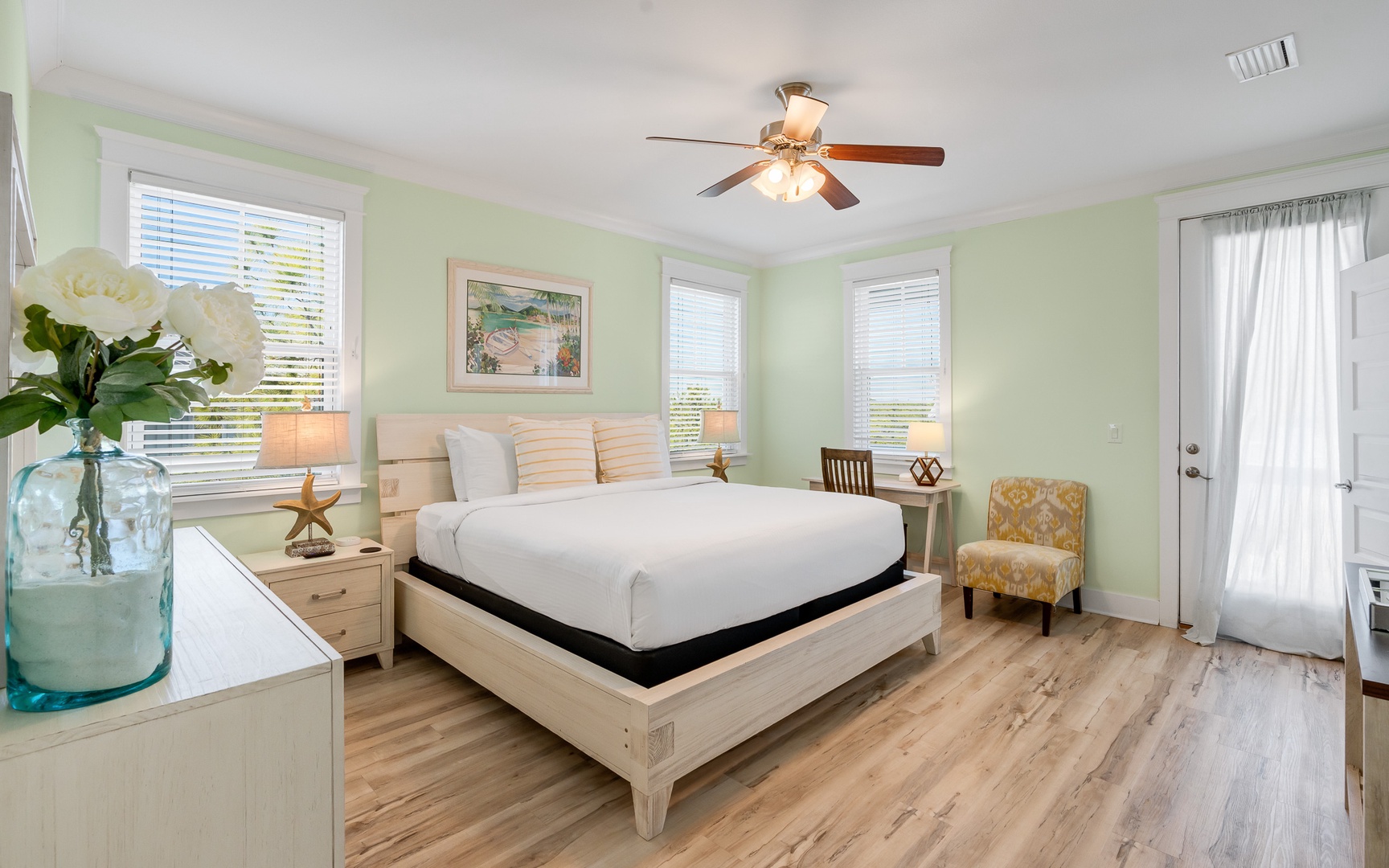 Unwind in your serene bedroom sanctuary with soft mint walls, elegant wood furnishings, and coastal accents that invite peaceful rest.