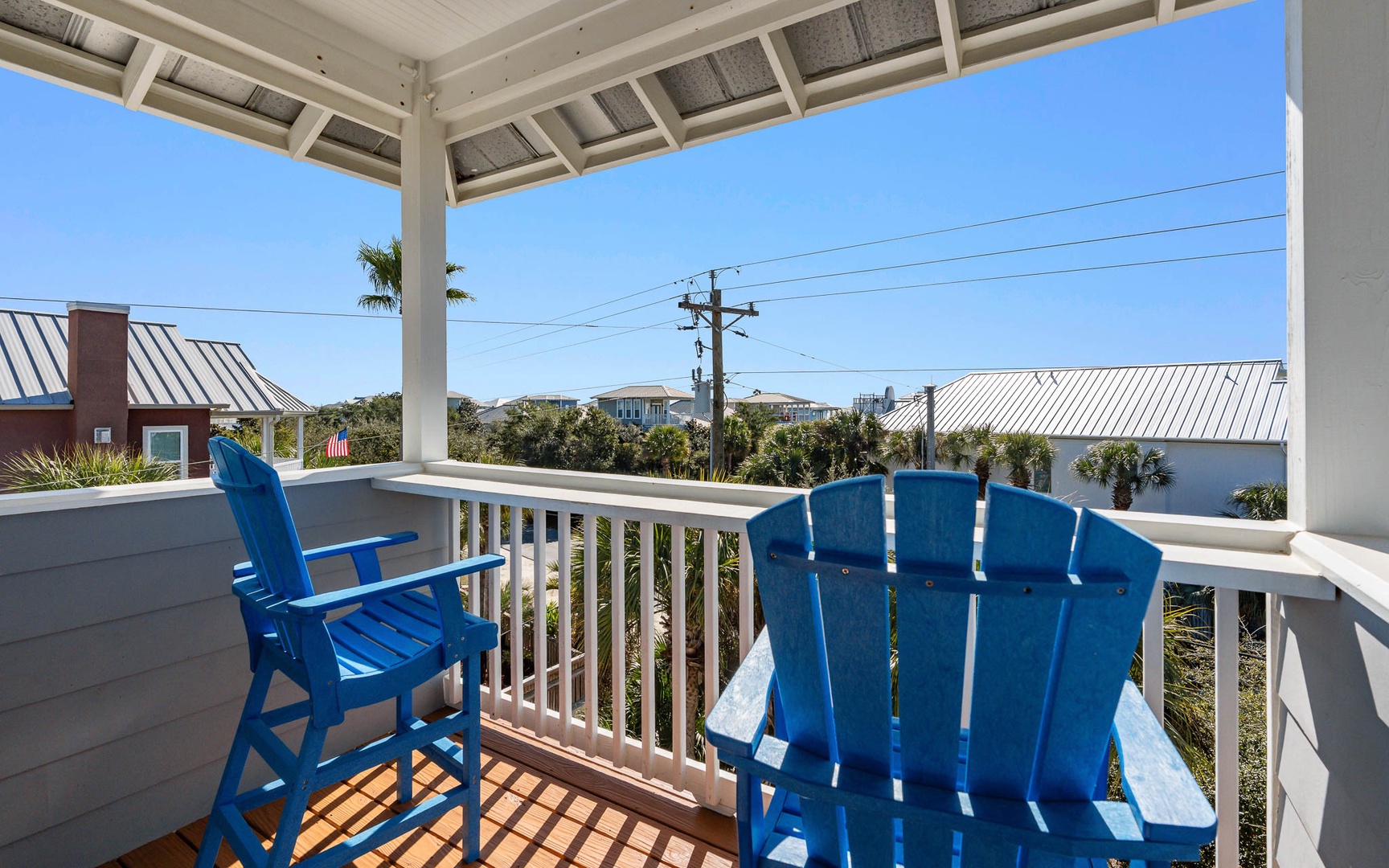 Unwind on your private covered balcony with bright blue Adirondack chairs, perfect for morning coffee or evening relaxation.